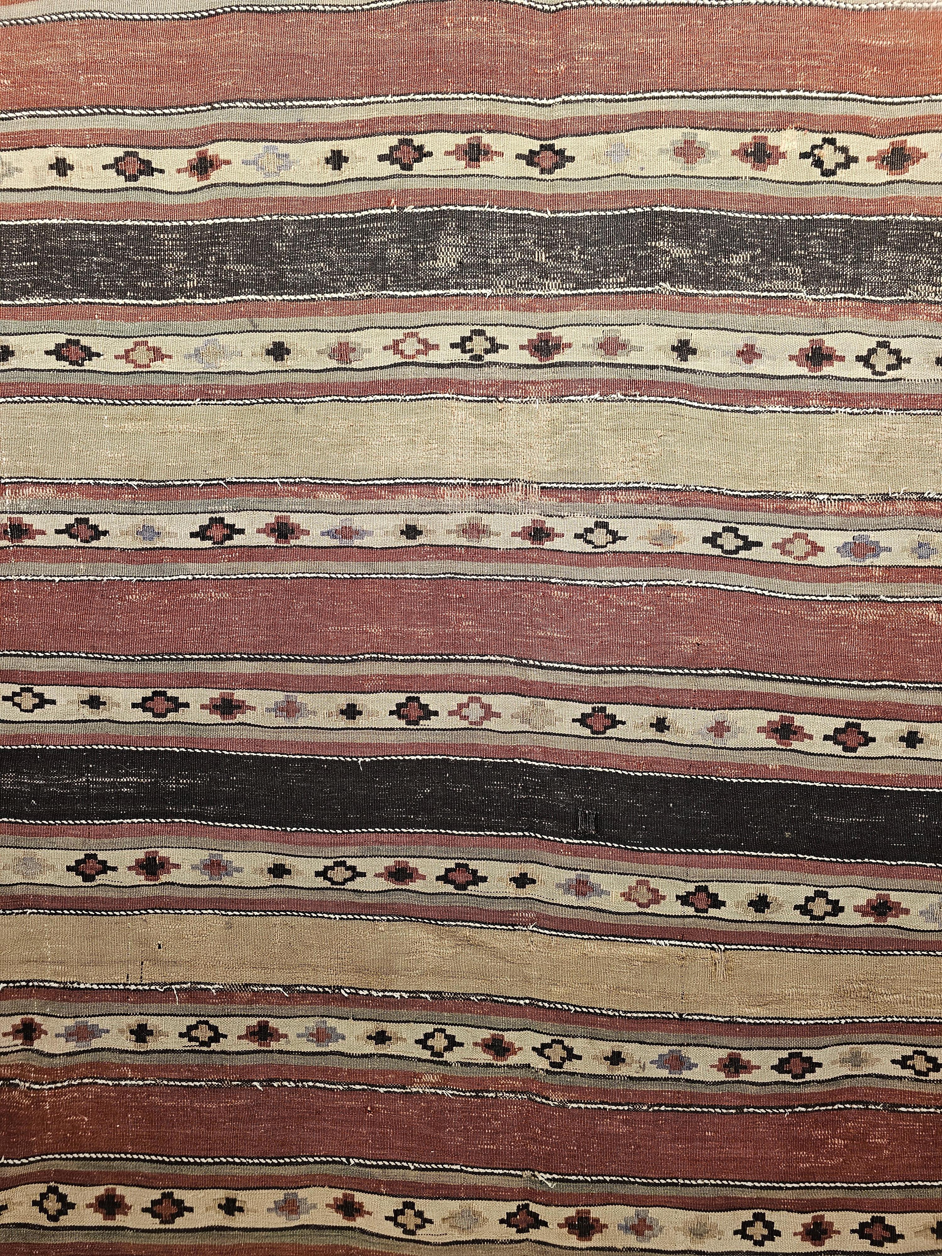 Early 1900s Persian Shahsavan Kilim with Southwestern Earth Tone Colors. The kilim has an alternating stripe design in black, brick red, ivory, and pale green with one stripe being in the solid color and the adjacent ones having small medallion