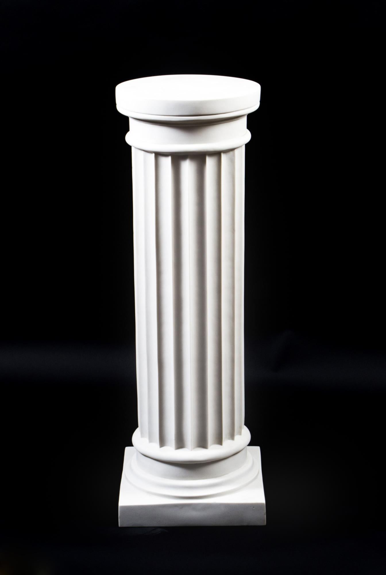 Un élégant piédestal vintage en forme de colonne dorique de l'Antiquité grecque classique datant de la fin du XXe siècle.

La colonne a un corps cannelé avec des chapiteaux unis et non décorés et se rétrécit légèrement en circonférence vers la