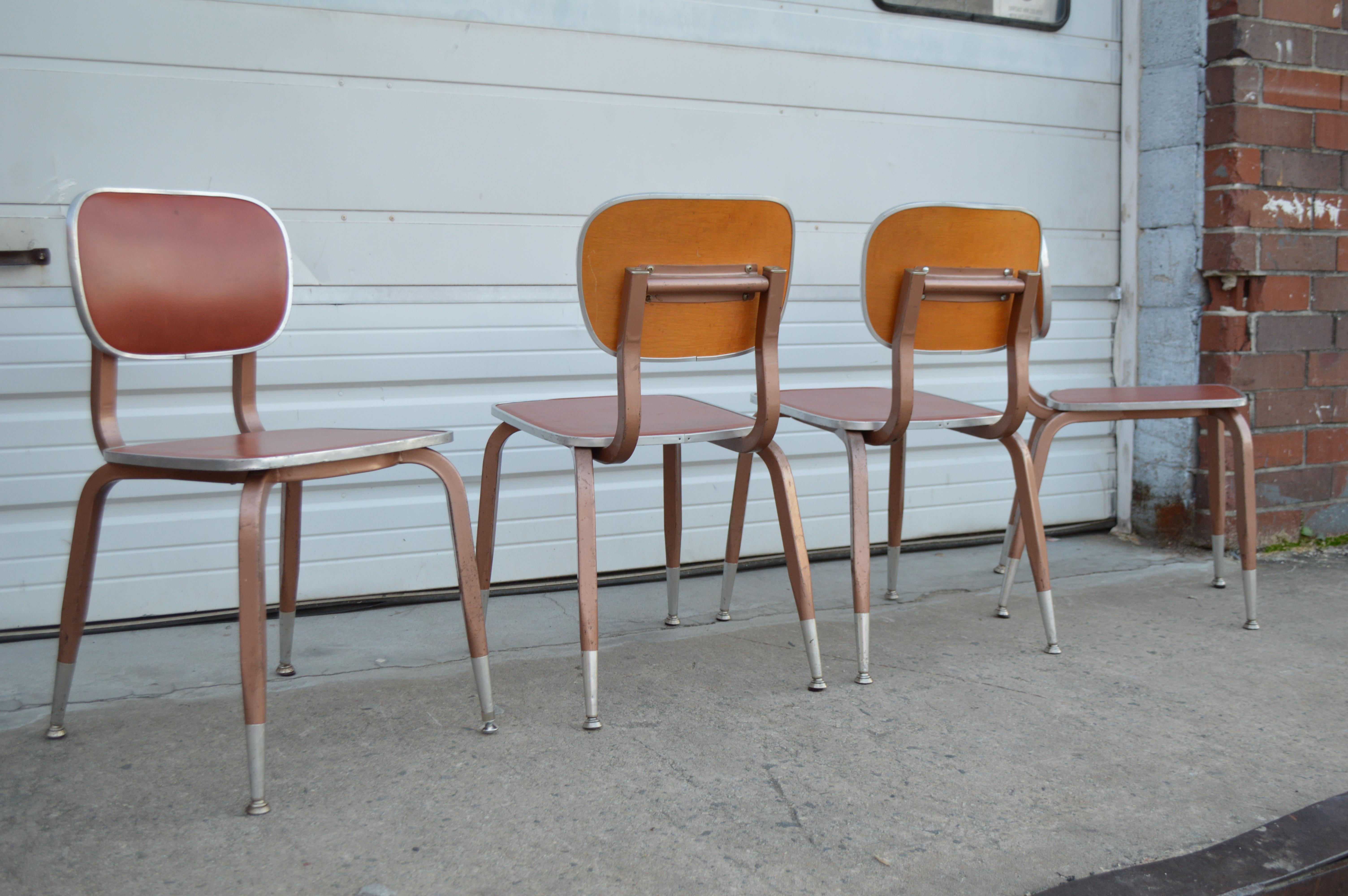 Set of four school style dining or side chairs made of vinyl, plywood, and aluminum. Nicely designed school chairs in style of Friso Kramer. Rust colored vinyl inside back and seat, aluminum frame, and plywood back.