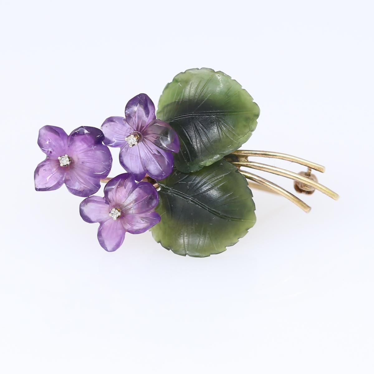 Violet flowers brooch comprising: Amethyst, Jade (jadeite) and Diamonds. Yellow gold. Three engraved amethyst flowers with a green leaf made of jadeite. In the centre of the flower, there is fine white Diamond. 
Once it was common to communicate a