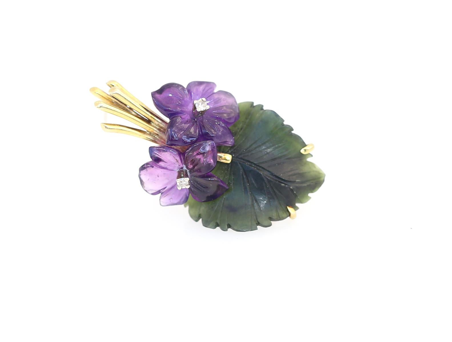 Violet flowers brooch comprising: Amethyst, Jade (jadeite) and Diamonds. Yellow gold. Two engraved amethyst flowers with a green leaf made of jadeite. In the centre of the flower, there is a fine white Diamond. 

Yellow Gold 585/000, 2 amethyst