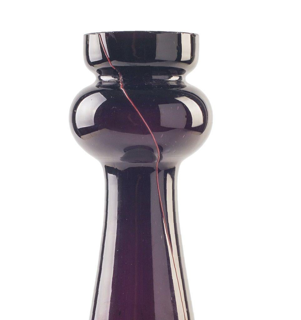 Dieser Kerzenhalter aus violettem Glas ist ein wunderschönes Stück Kunstglas, das in den 1970er Jahren in einer nordeuropäischen Manufaktur hergestellt wurde.

Dieser dekorative Kerzenhalter mit roten Fäden und weiß getupftem Sockel ist in sehr