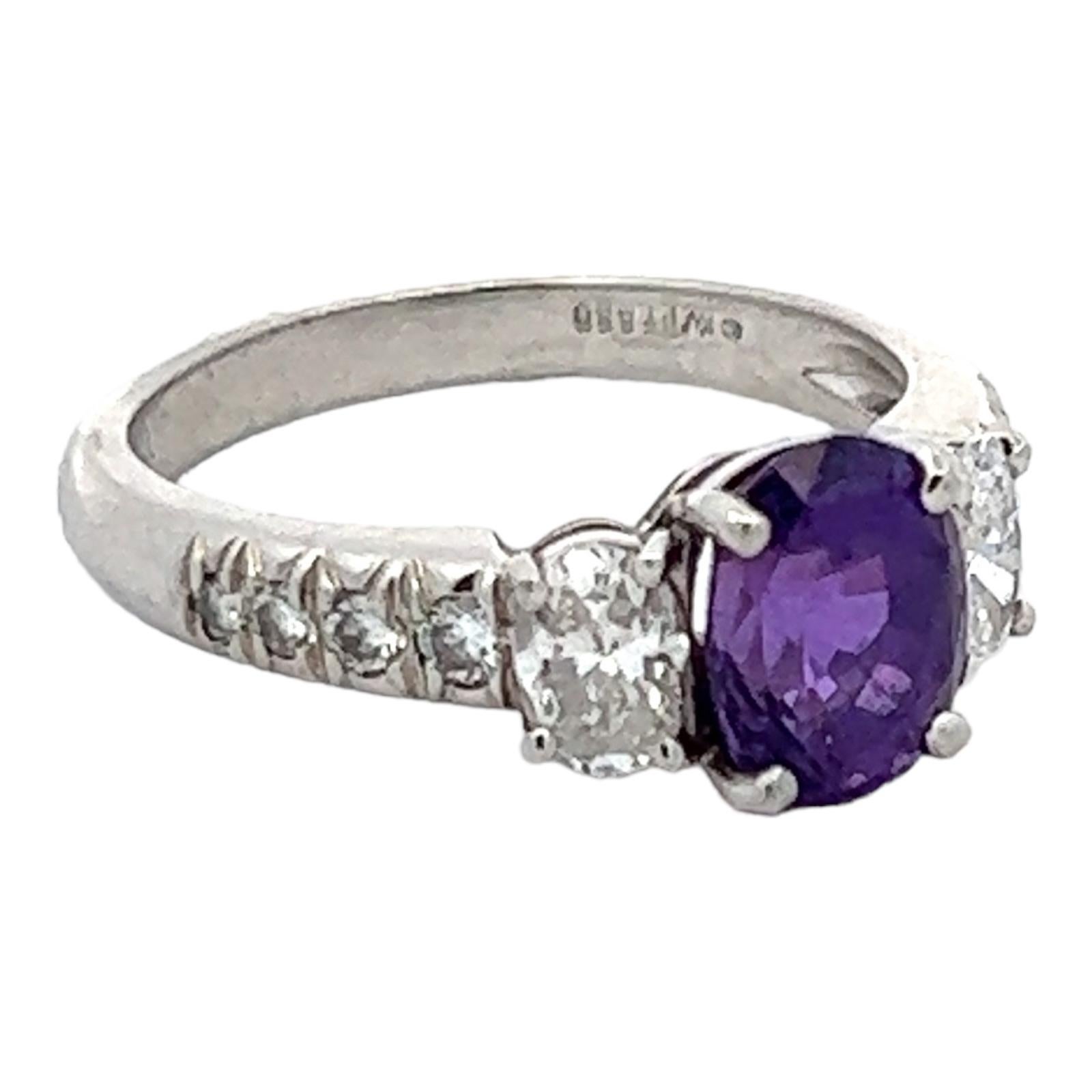 Unique natural violet color sapphire diamond ring handcrafted in platinum. The ring features an oval violet sapphire gemstone weighing approximately 1.00 carat. The sapphire is flanked by two oval diamonds weighing approximately .50 CTW and another