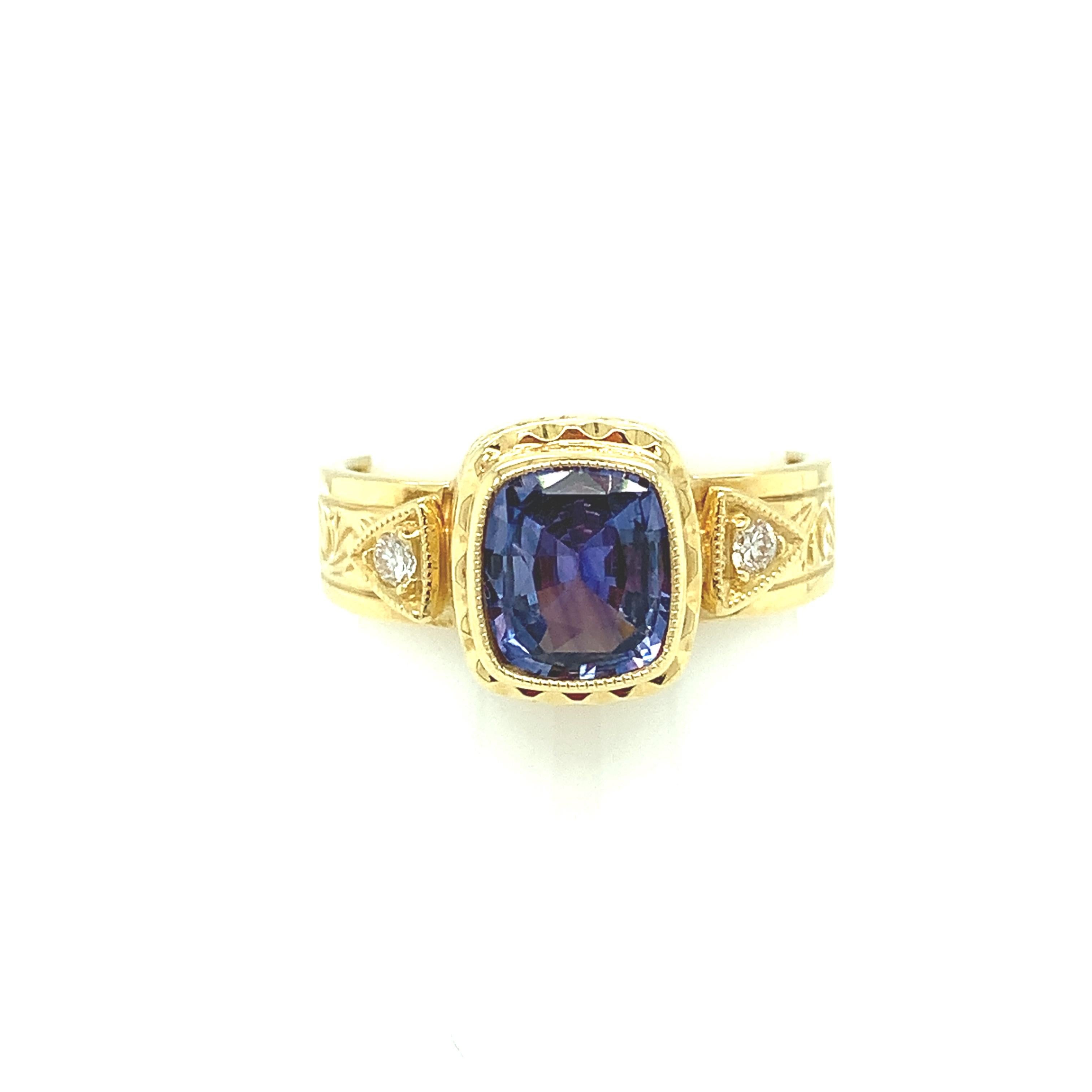 A beautiful, African-violet color sapphire is showcased in this beautifully engraved 18k yellow gold ring which is one of our signature styles. The sapphire is remarkably brilliant and has been bezel set with impeccable precision and finished with