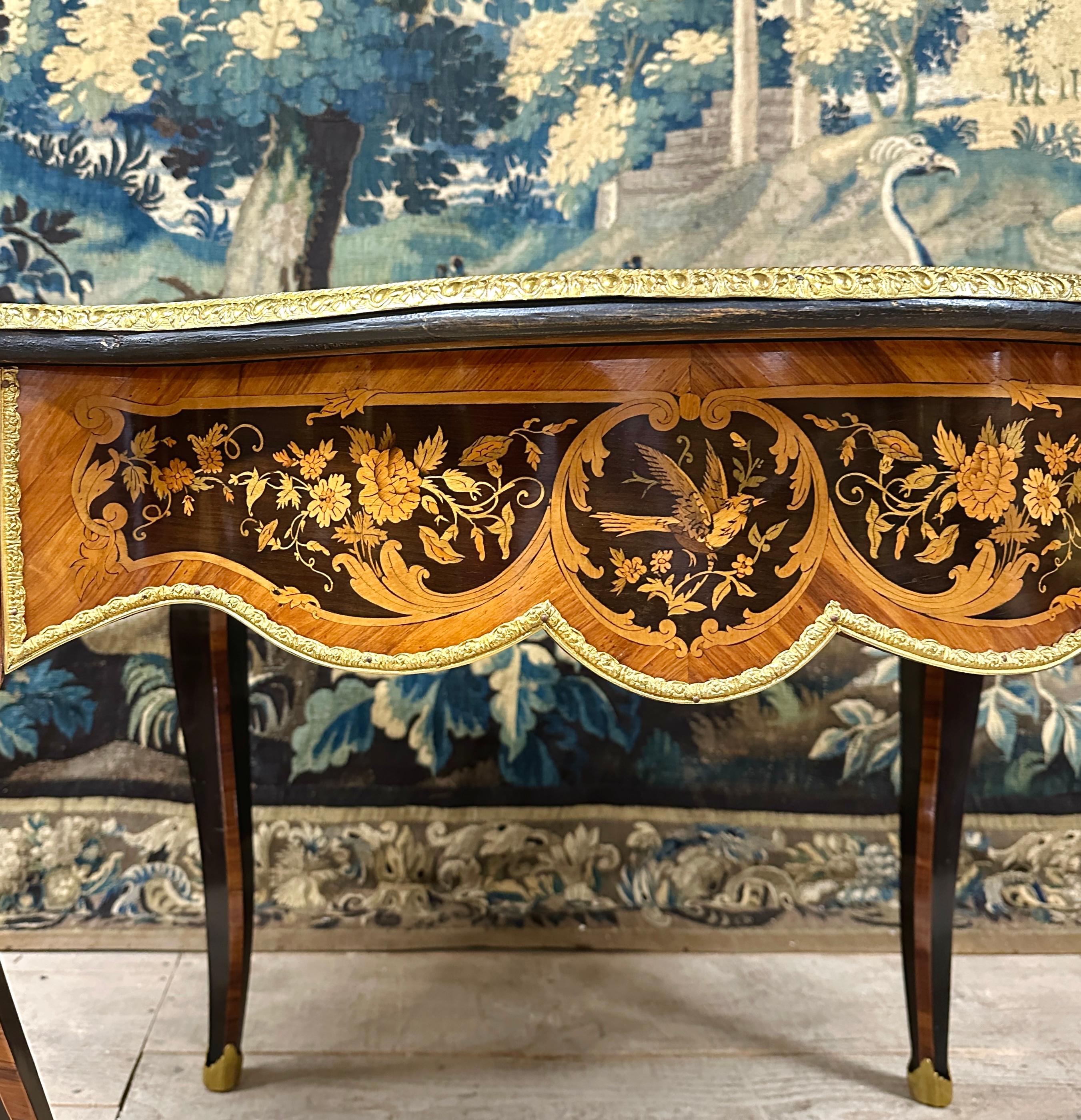 Riche table formant bureau, ouvrant par un tiroir en frise. Travail de style Louis XV d'époque Napoléon III avec un très beau plateau décoré de feuillages, fleurs, oiseaux dans des cartouches. Cette table est fabriquée à partir de nombreuses