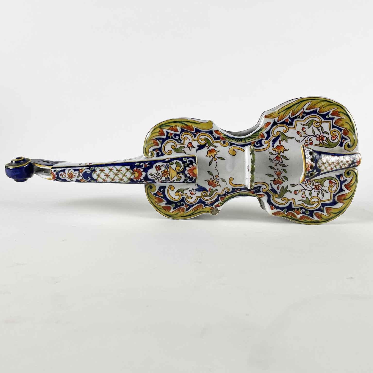 Violín en loza fabricación francesa de Rouen Principios de 1800 con un bolsillo lateral y dos agujeros para colgar en la pared por una cuerda, falta.  Este violín de mayólica vidriada estannífera está completamente decorado en tonos ocres y azules
