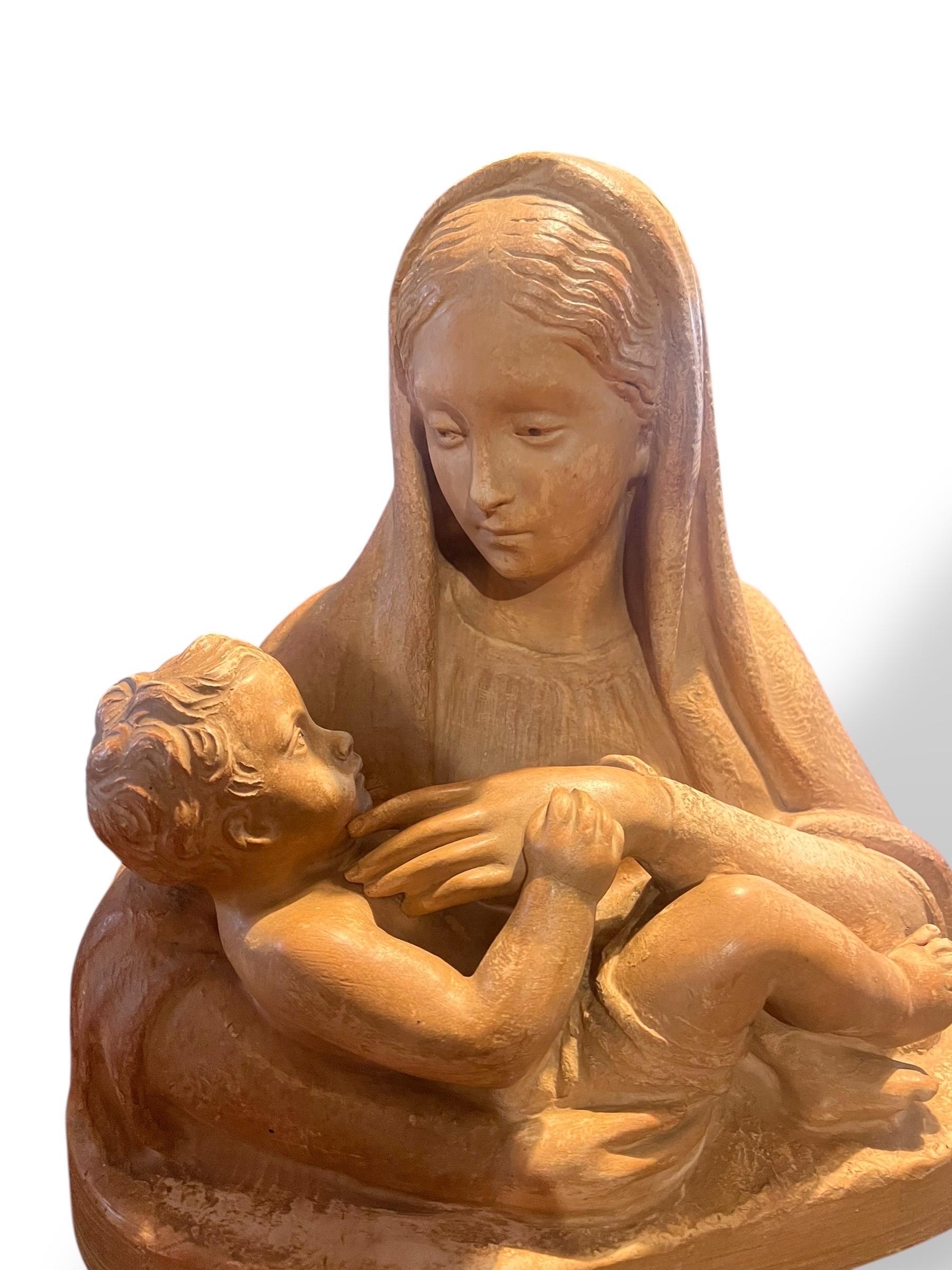 Eine rührende Terrakotta-Skulptur, die die Jungfrau Maria mit dem Jesuskind in den Armen darstellt, signiert M. Normand auf dem Sockel. Das um 1890-1910 entstandene zarte Werk veranschaulicht die Sensibilität des religiösen Naturalismus am Ende des