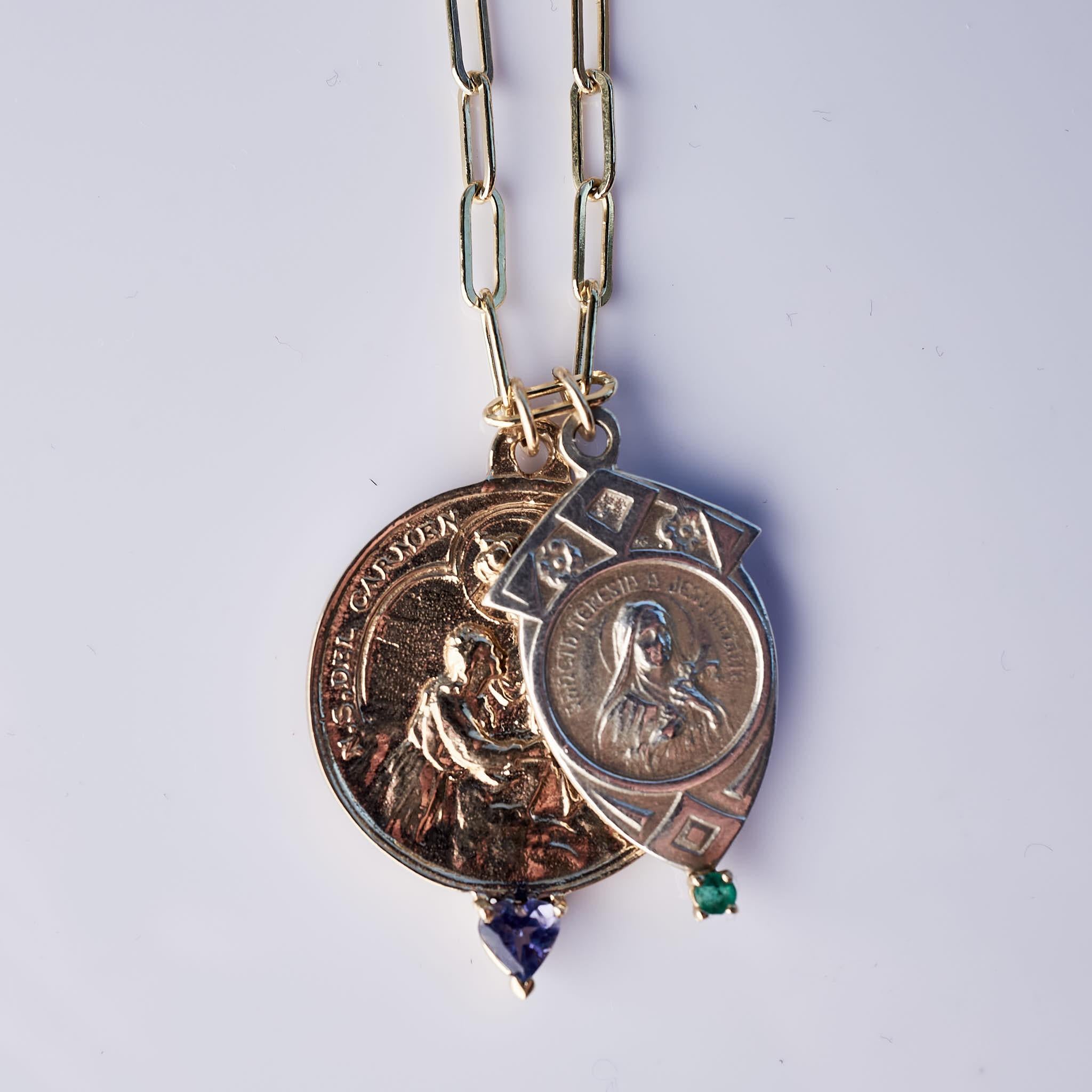 Ce collier à double médailles, composé de deux médailles de la Vierge Marie, est suspendu à une chaîne remplie d'or. L'une des médailles est ronde en bronze et comporte une tanzanite en forme de cœur sertie d'or. L'autre médaille est en argent