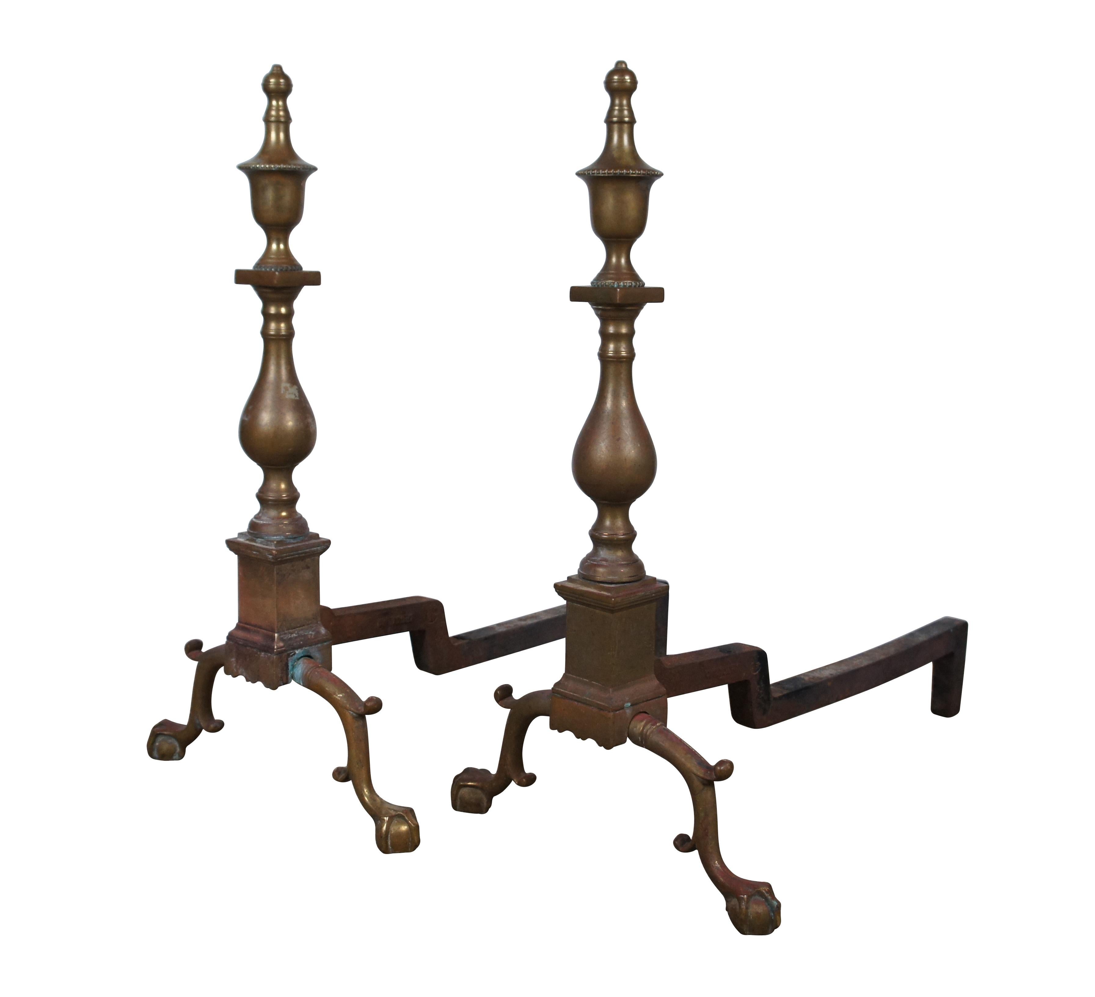 Mid Century iron and brass andirons / firedogs by Harvin / Virginia Metalcrafters for the Colonial Williamsburg Restoration line of products. Features colonial styling with scrolled ball and claw feet and baluster shape with trophy urn tops. Item
