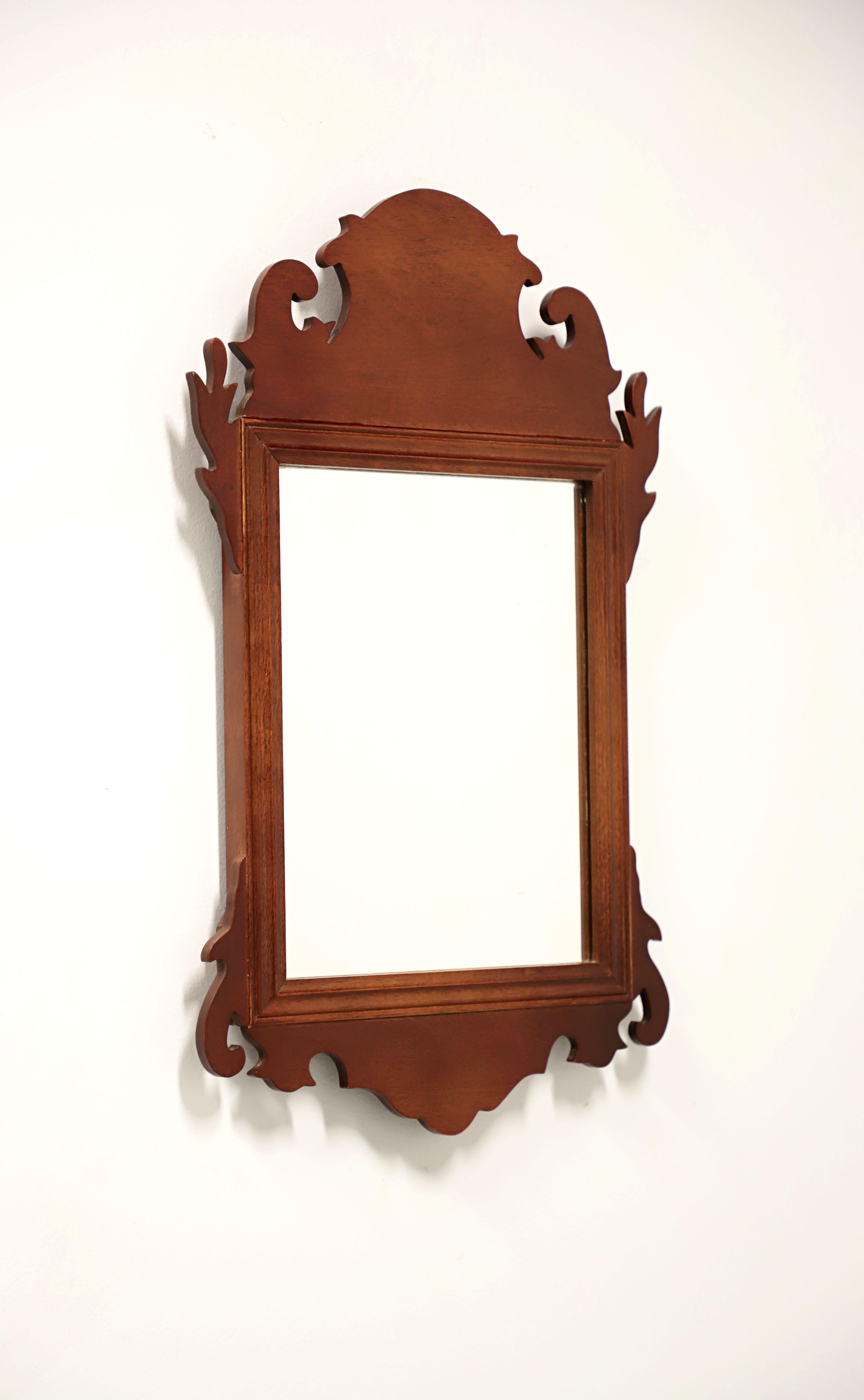 A Chippendale style petite wall mirror by Virginia Metalcrafters, from their Colonial Williamsburg Reproductions made exclusively for Colonial Williamsburg. Mirrored glass, mahogany frame with decorative carving to top and bottom. Made in the USA,