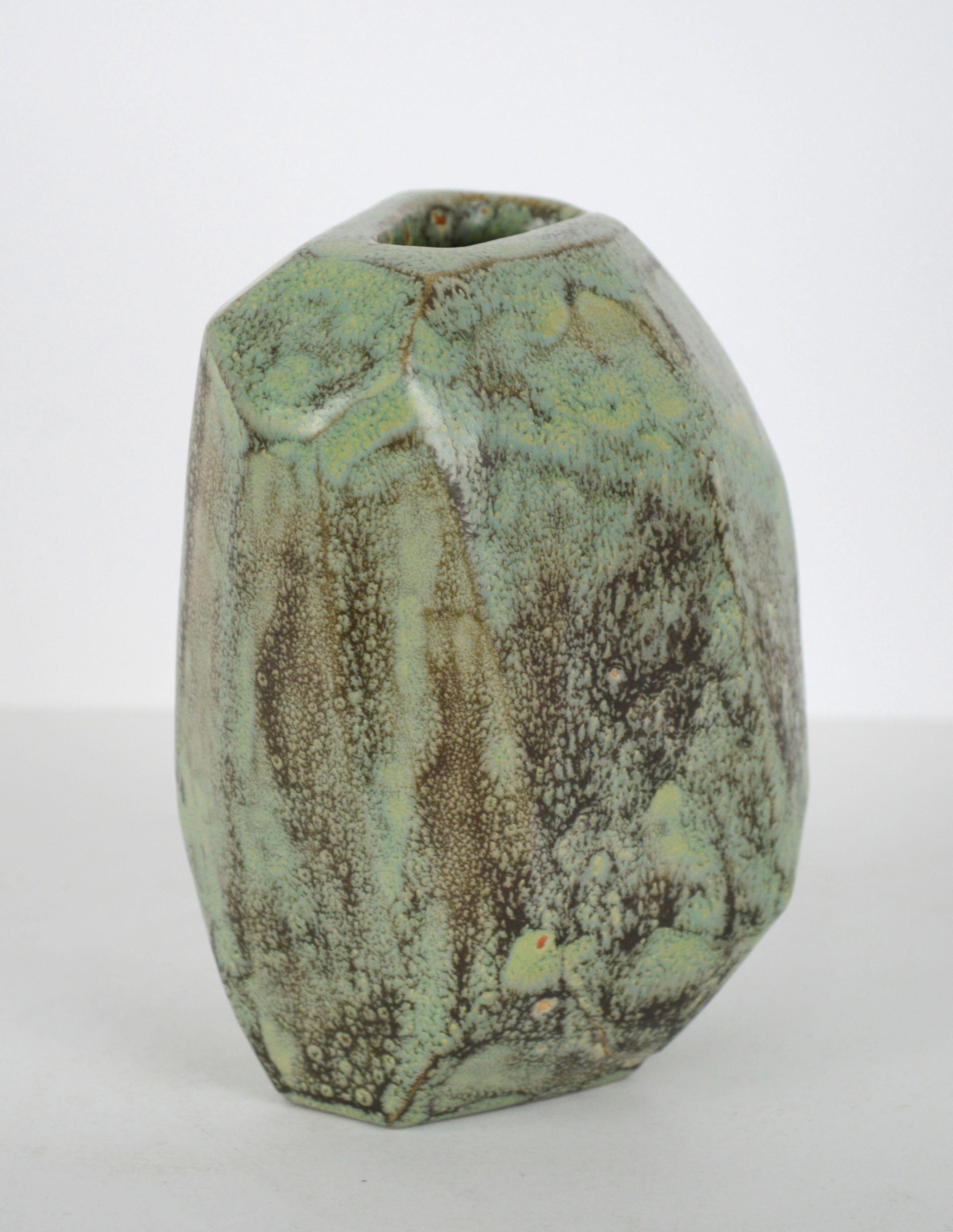 Gorgeous abstract ceramic sculptural vase shaped into a unique organic yet modern form, with turquoise and earth-toned glazes that naturally blend together an catch the light at different angles of the vase's geometric planed surface, by