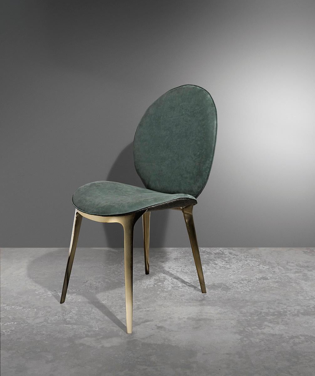 Chaise rembourrée avec une coque en bois incurvée, tapissée et recouverte de cuir ou de tissu. Les pieds en fonte d'aluminium sont disponibles dans la sélection de finitions métalliques.Le dossier est également disponible dans la version