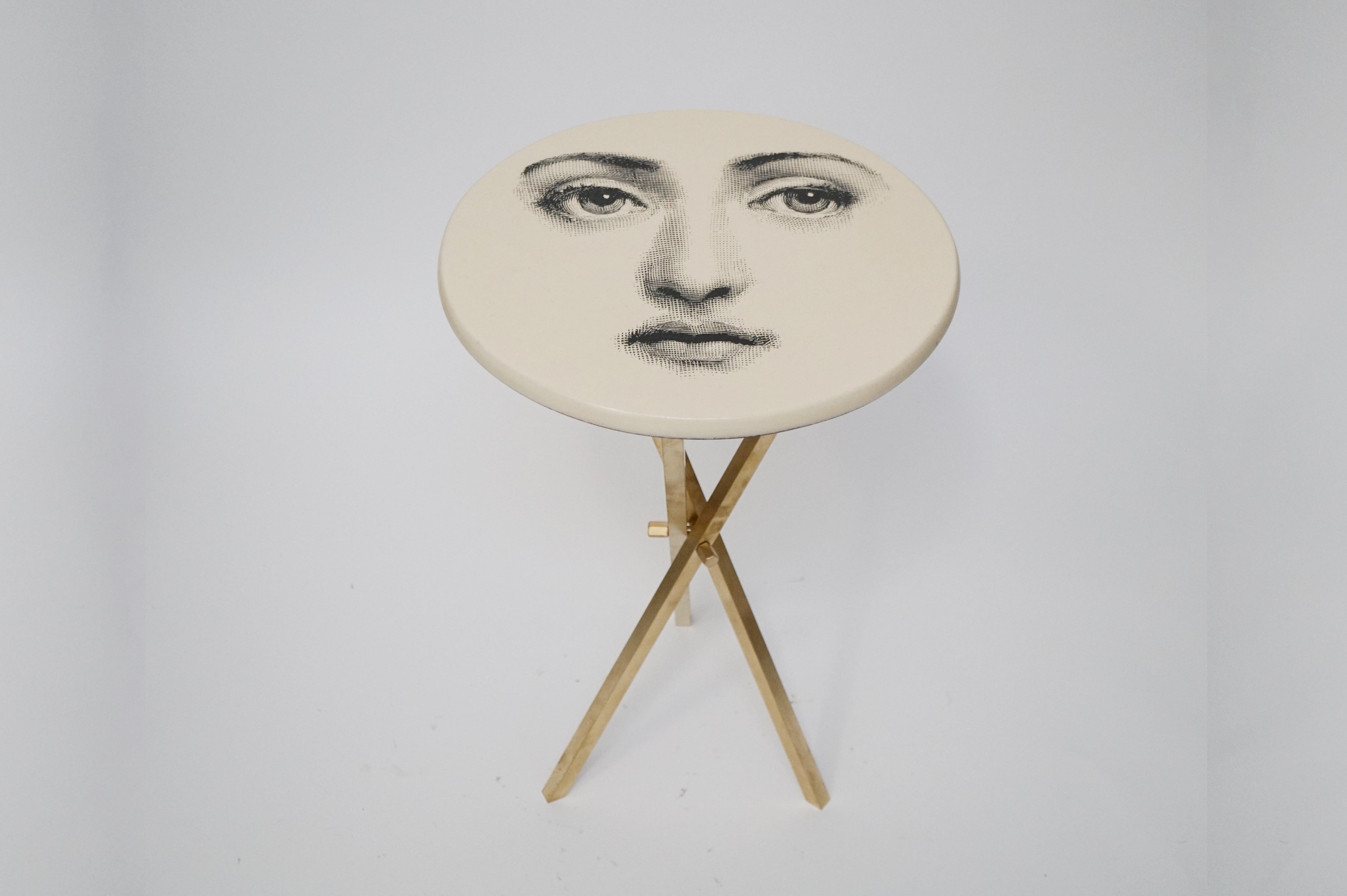 This fun and whimsical collectors item is a side table by Piero Fornasetti, signed underneath with its original label. The side table is affixed on top of a brass tri-pod base which is removable for easy and economical shipping or