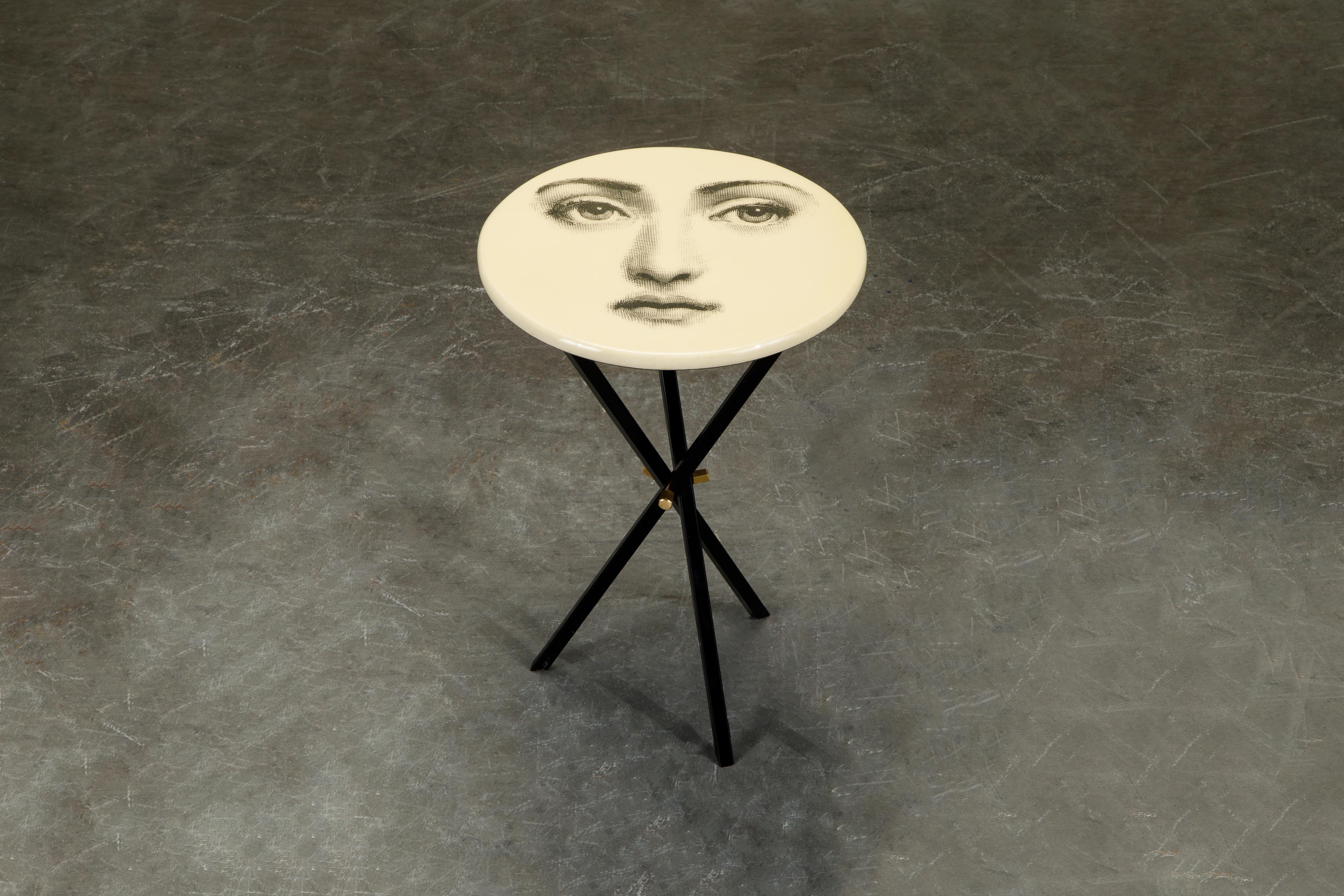 This fun and whimsical collectors item is a side table by Piero Fornasetti, signed underneath with its original label. The side table is affixed on top of a brass tri-pod base which is removable for easy and economical shipping or transport. 

A