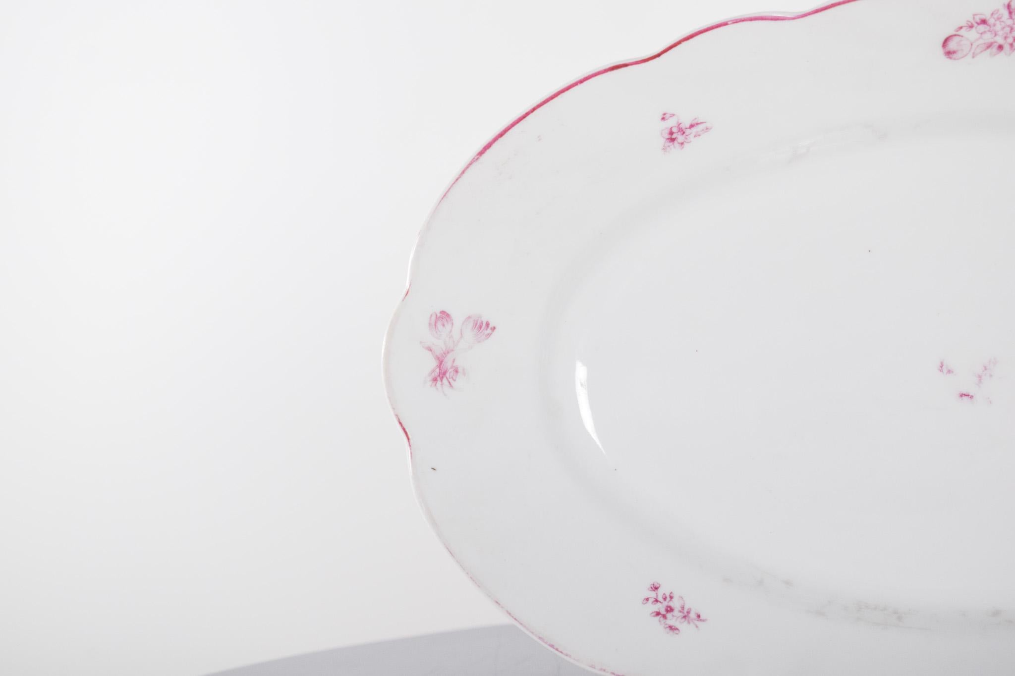 Cut-out platter in Vista Alegre porcelain. With an oval shape and gently undulating edges, the piece has a classic and refined design. The white background serves as a base for discreet pink floral details, strategically distributed along the edge