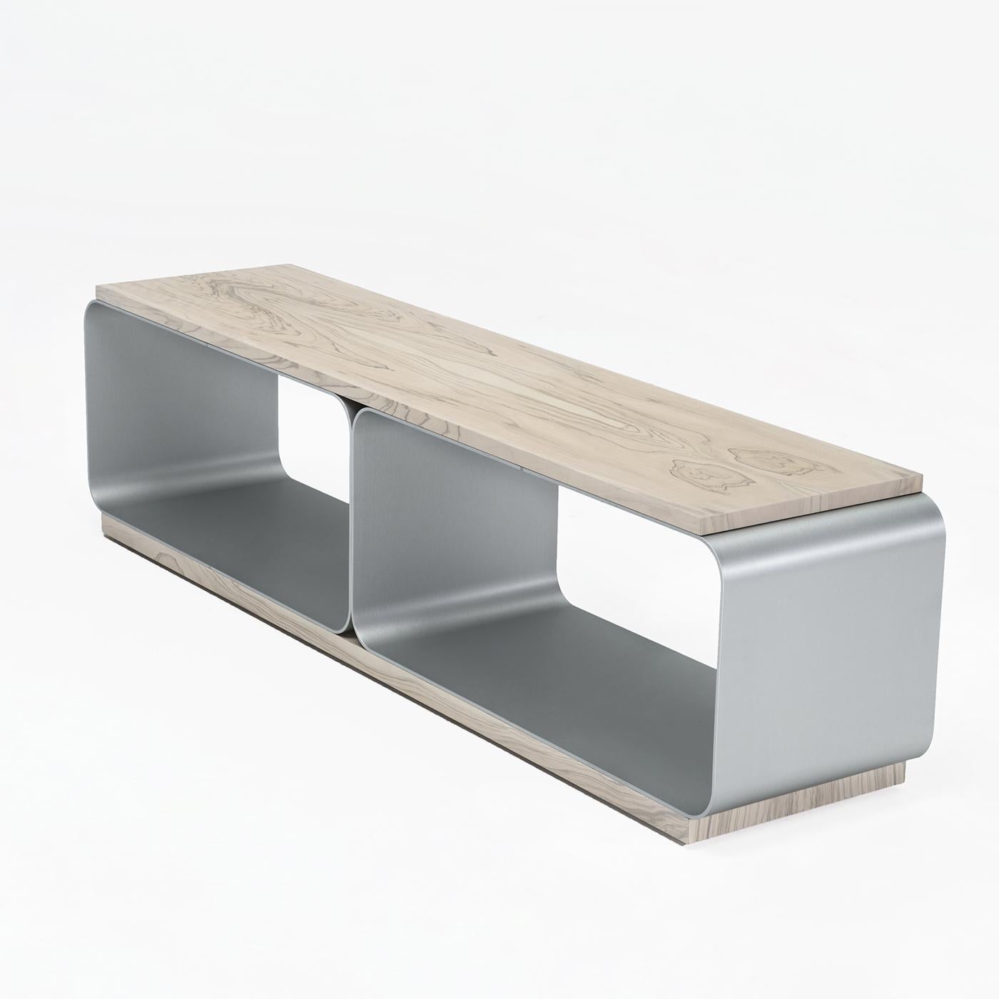This bench is composed of two satin anodized aluminum supporting structures covered by an olive wood top with whitened finish. The two compartment, hollowed out base can be used to store shoes, books or other objects, making the item stylish and