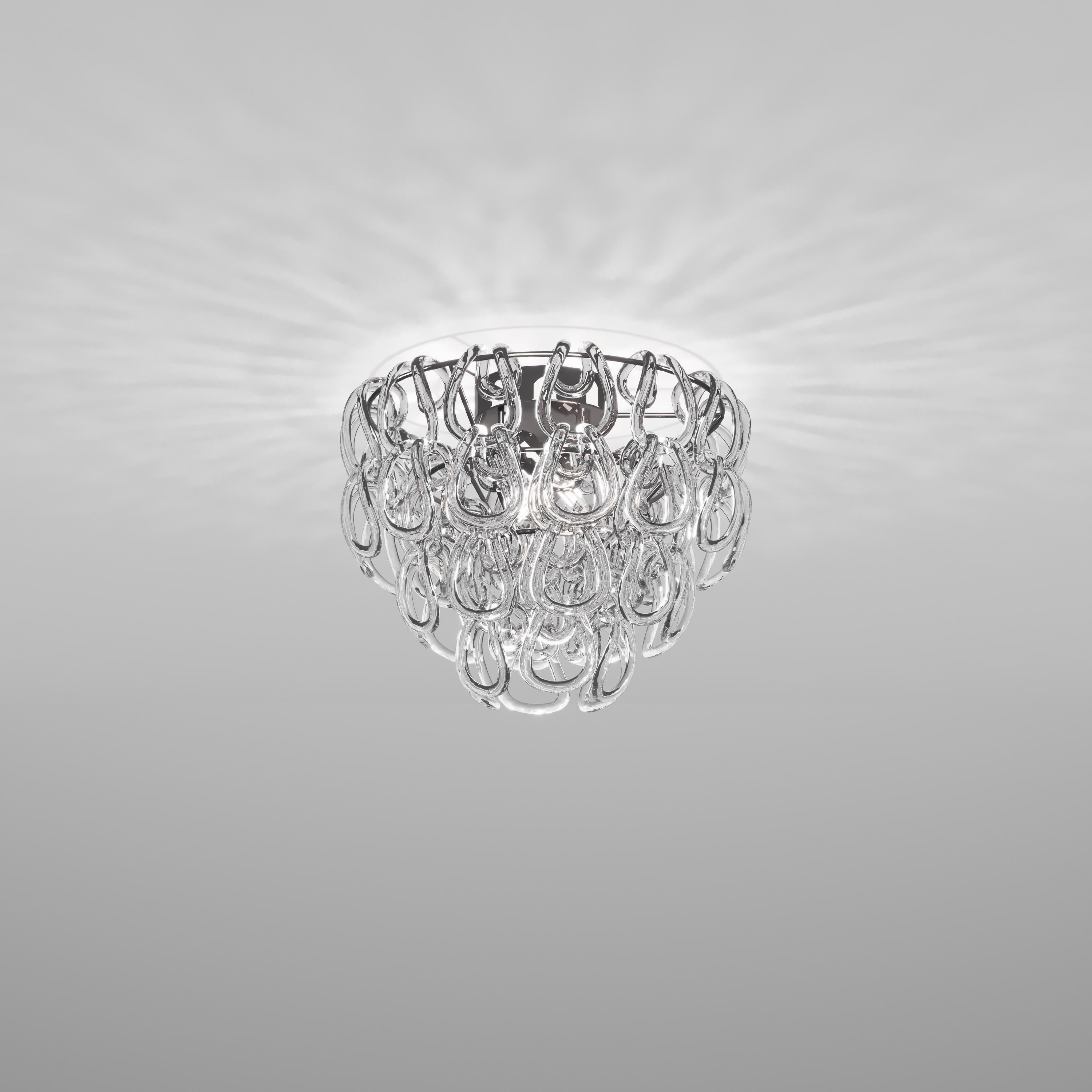Un élément pur : le crochet en cristal. C'est l'intuition d'un maître du design italien, Angelo Mangiarotti, qui a créé en 1967 le best-seller du catalogue Vistosi, Giogali. Un entrelacement iconique appliqué à la version que l'on