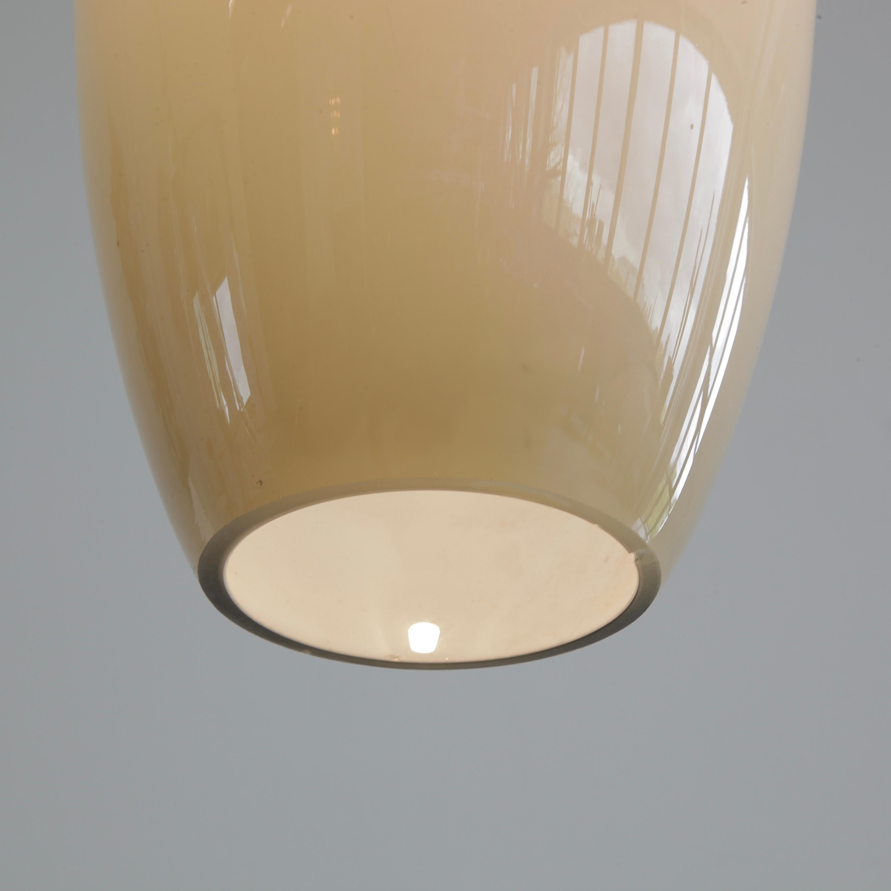 Glass tube pendant by Alessandro Pianon. Italy, Vistosi, 1960s.

Beautifully shaped glass pendant, hand blown on Murano and produced by Vistosi. The glass is of a warm shade of grey with white lining on the inside. One light fitting has three