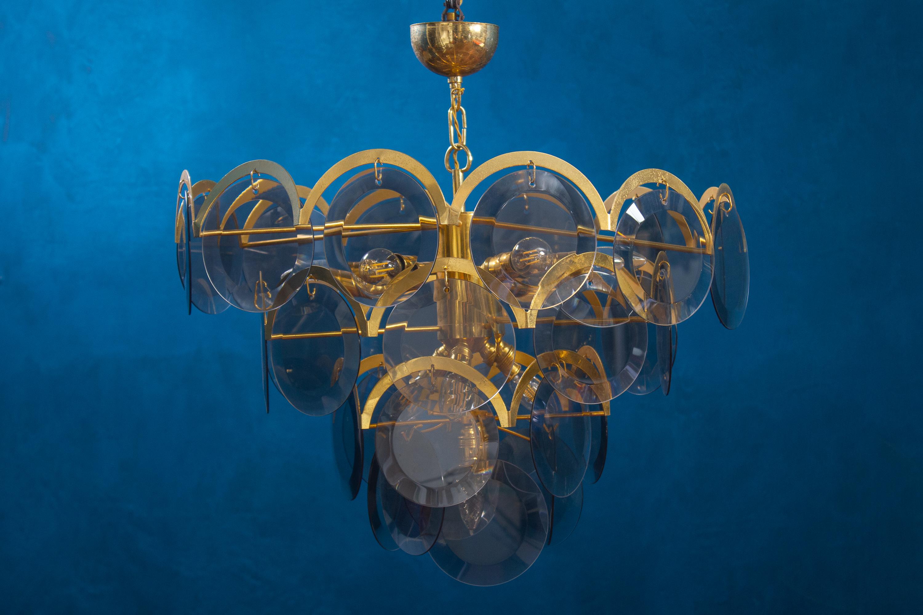 Spectacular chandelier by Vistosi made with 48 grey fumé beveled Murano discs a four levels.
The cage and armature are original brass. Each glass disk is 6