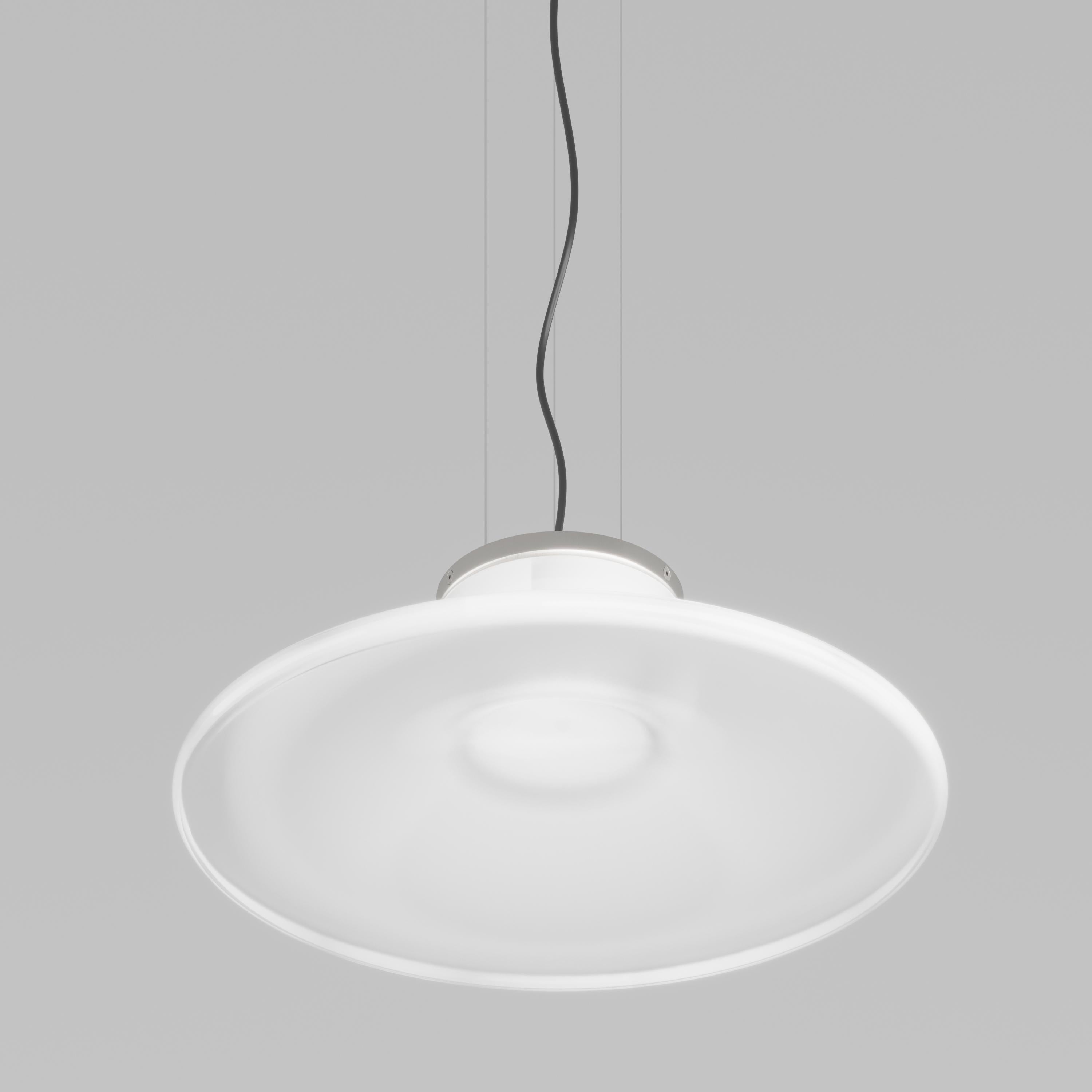 White crystal corollas. The stem develops thinly and then opens up in a mouth with crystal profiles. The LED source lights up the white shaded glass of the suspension and ceiling lamp versions. Neutral tones and simple, elegant lines make it
