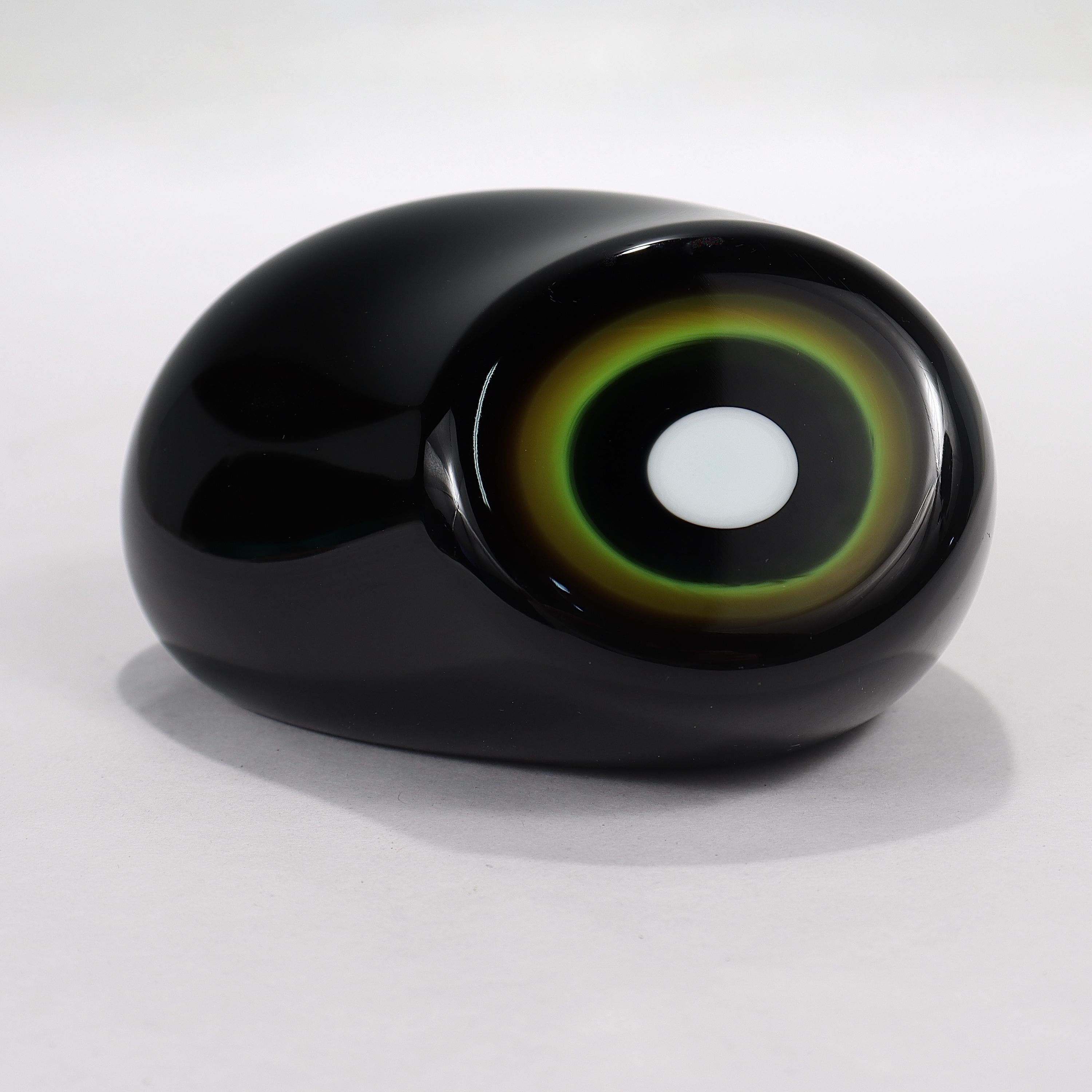 A fine Murano glass paperweight.

By Vistosi.

In the form of a black (or deep amethsyt) ameoba shape with a green & white bullseye pattern.

Simply a great Italian glass paperweight! 

Date:
1960s - 70s

Overall Condition:
It is in