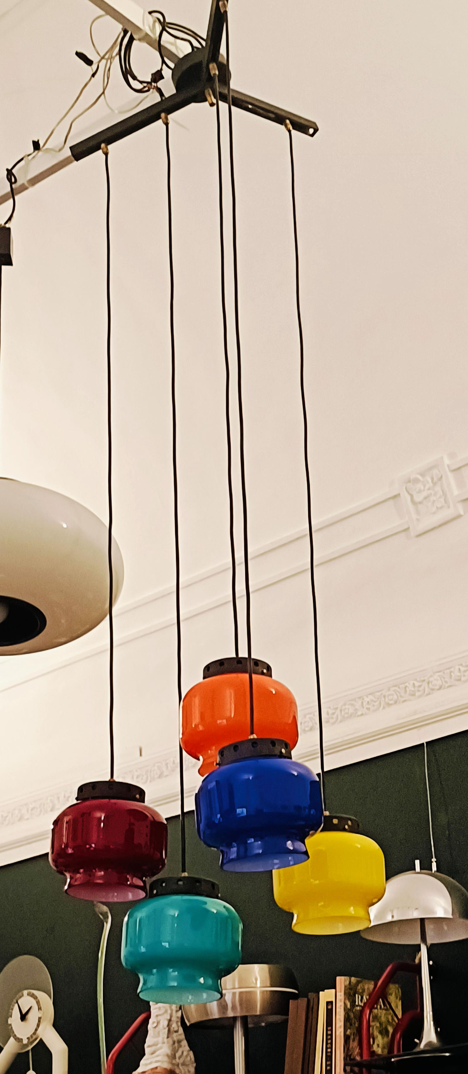 Lampadario ad elementi pendenti in vetro colorato di Murano ed interno bianco lattimo, struttura in metallo nero con dettagli in ottone, Vistosi anni 60.