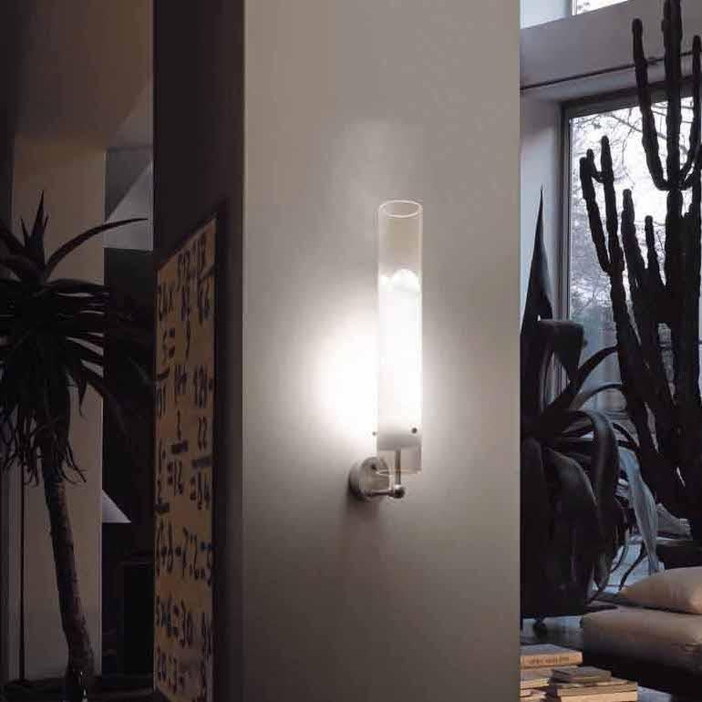 Wall sconce with a minimal, unobtrusive design that makes the most of the light source, thanks to the translucent white band inserted in the glass E26 lighting.