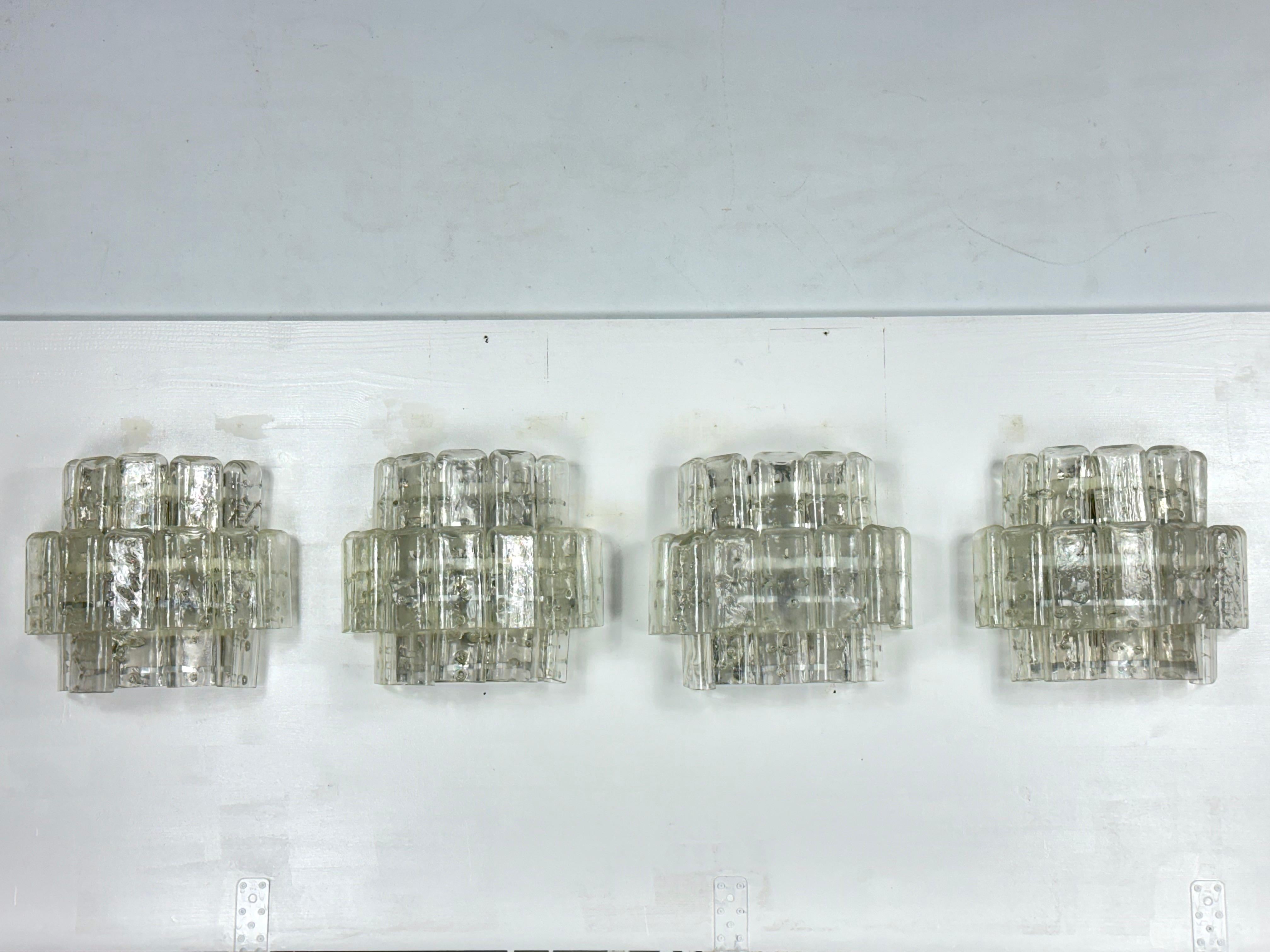 Set di quattro grandi lampade da parete in vetro trasparente di Murano prodotte in Italia negli anni '70. Attribuibile a Vistosi. Nessuna etichetta o marchio. Ottime condizioni vintage senza scheggiature o crepe, staffe in metallo con normali tracce