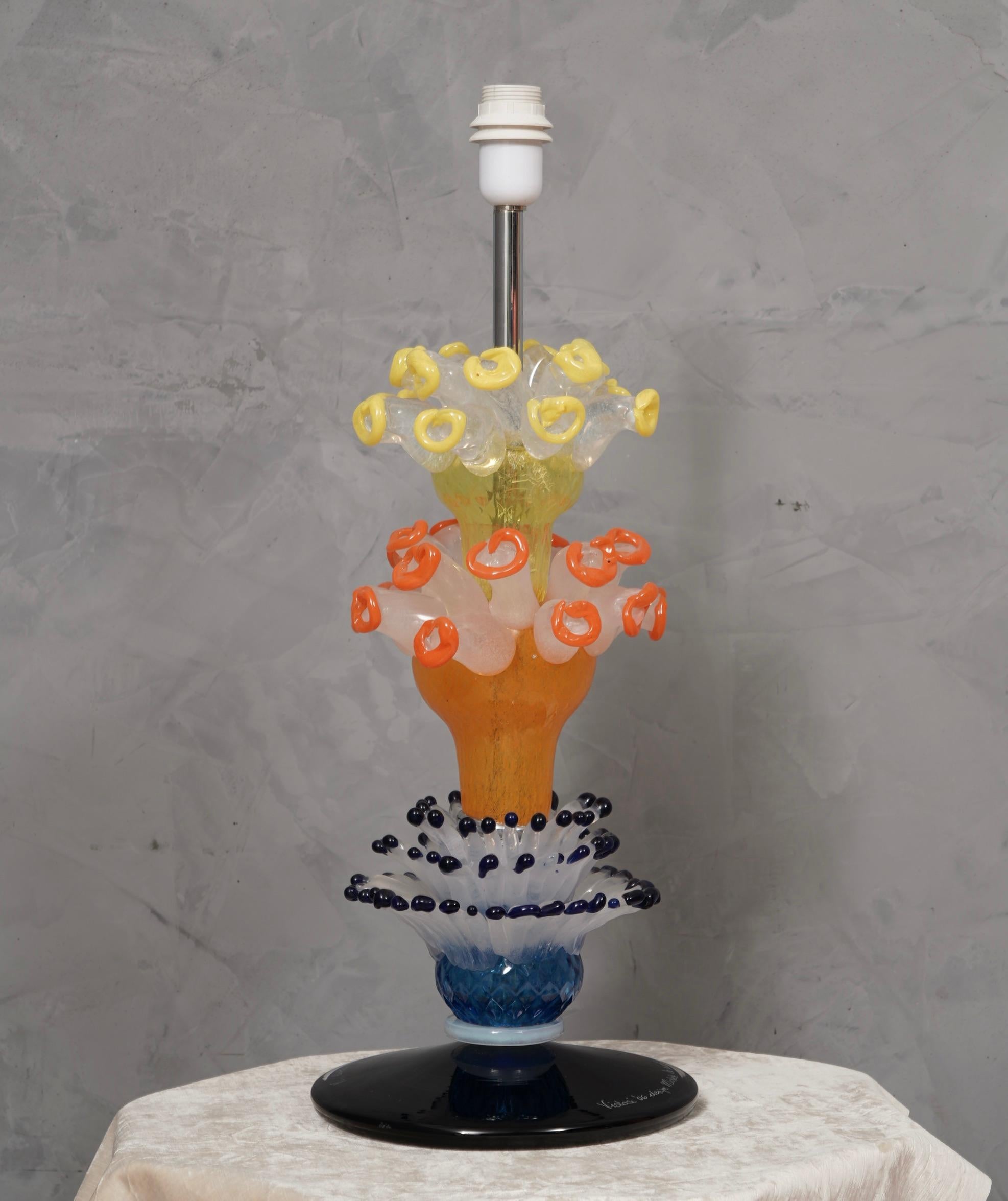 Elegante und sehr originelle Tischleuchte, entworfen von Michele De Lucchi für Vistosi, mit einem sehr starken, reichen und präsenten Charakter, der sich sehen lassen kann.

Die Tischlampe besteht aus vier verschiedenen Teilen; von unten beginnend