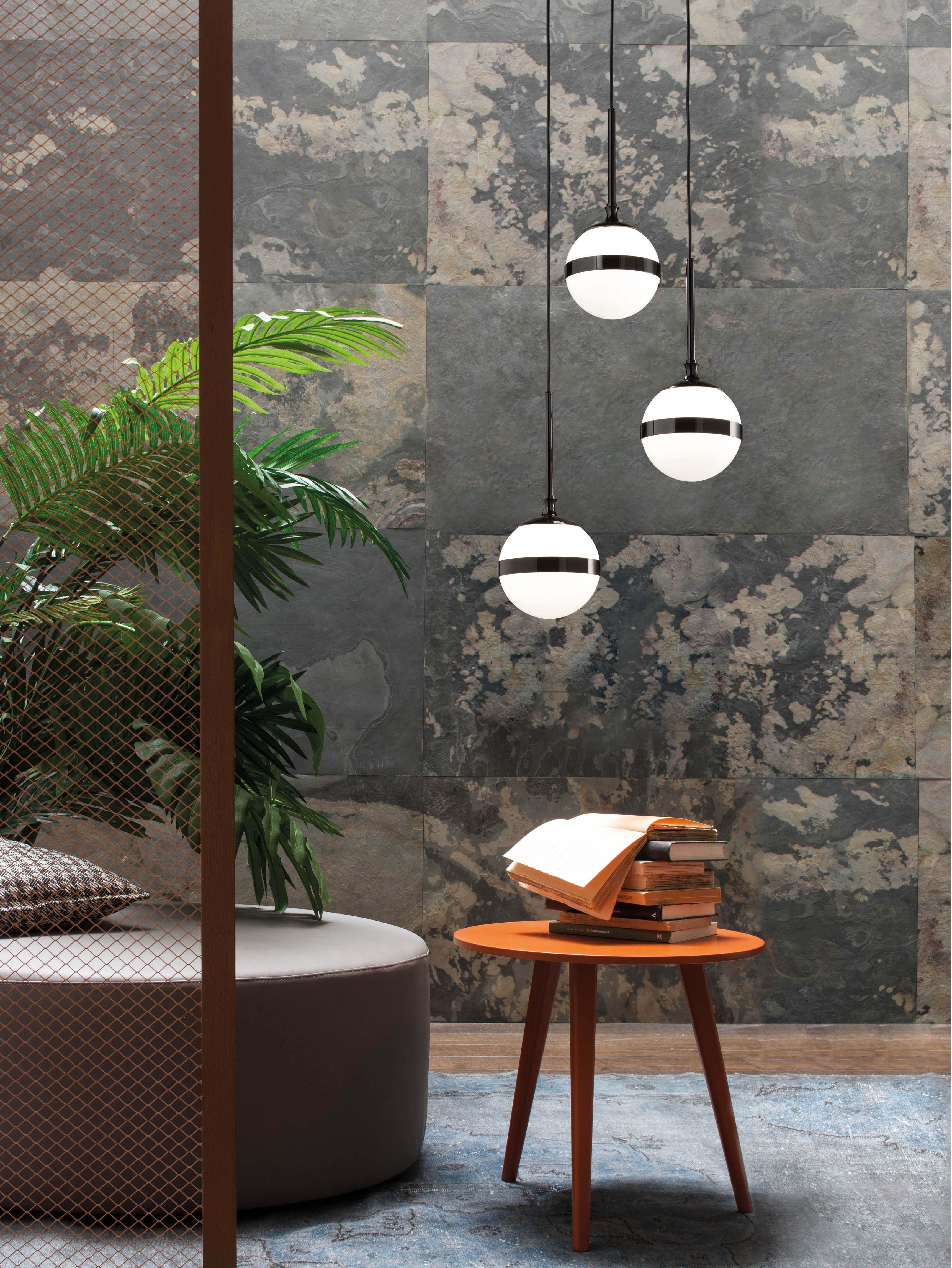 El vidrio blanco, soplado a mano, junto con el metal negro brillante, con un tratamiento efecto plomo, interpretan la polaridad entre el blanco y el negro con la ligereza de un diseño racional y elegante. Con una impresionante instalación, el