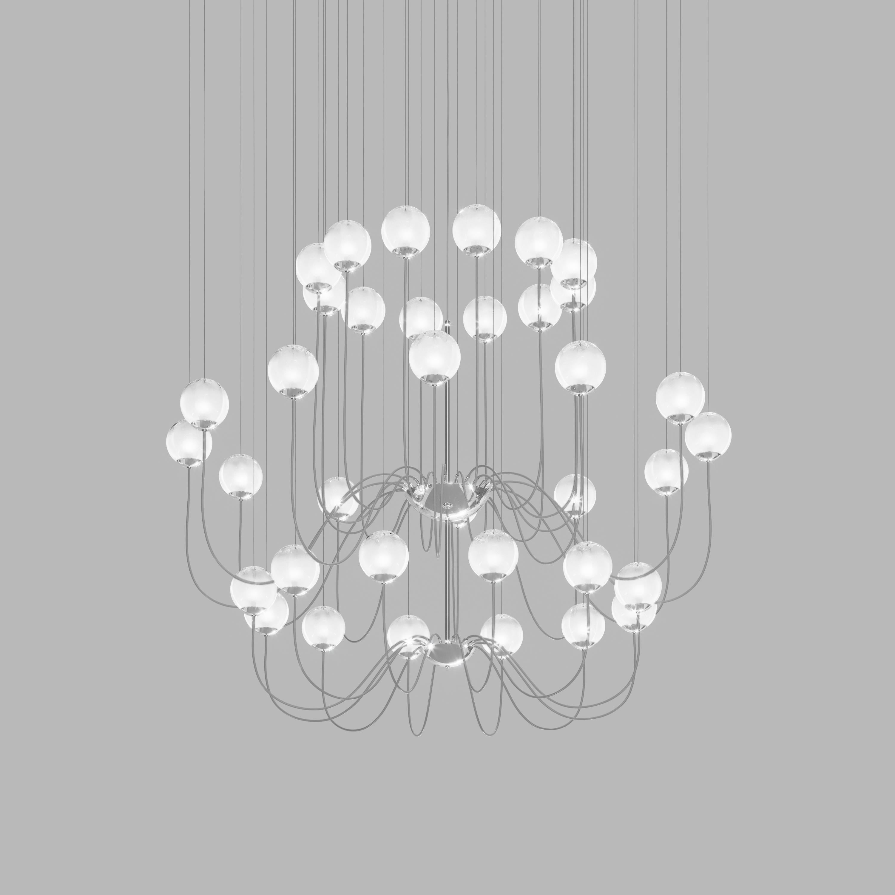 Collection of lamps with a blown and irregular striped glass diffuser. The three sizes of the spheres and the different cable heights are designed to create elegant compositions. The chandelier version allows to fix the diffusers with steel cables