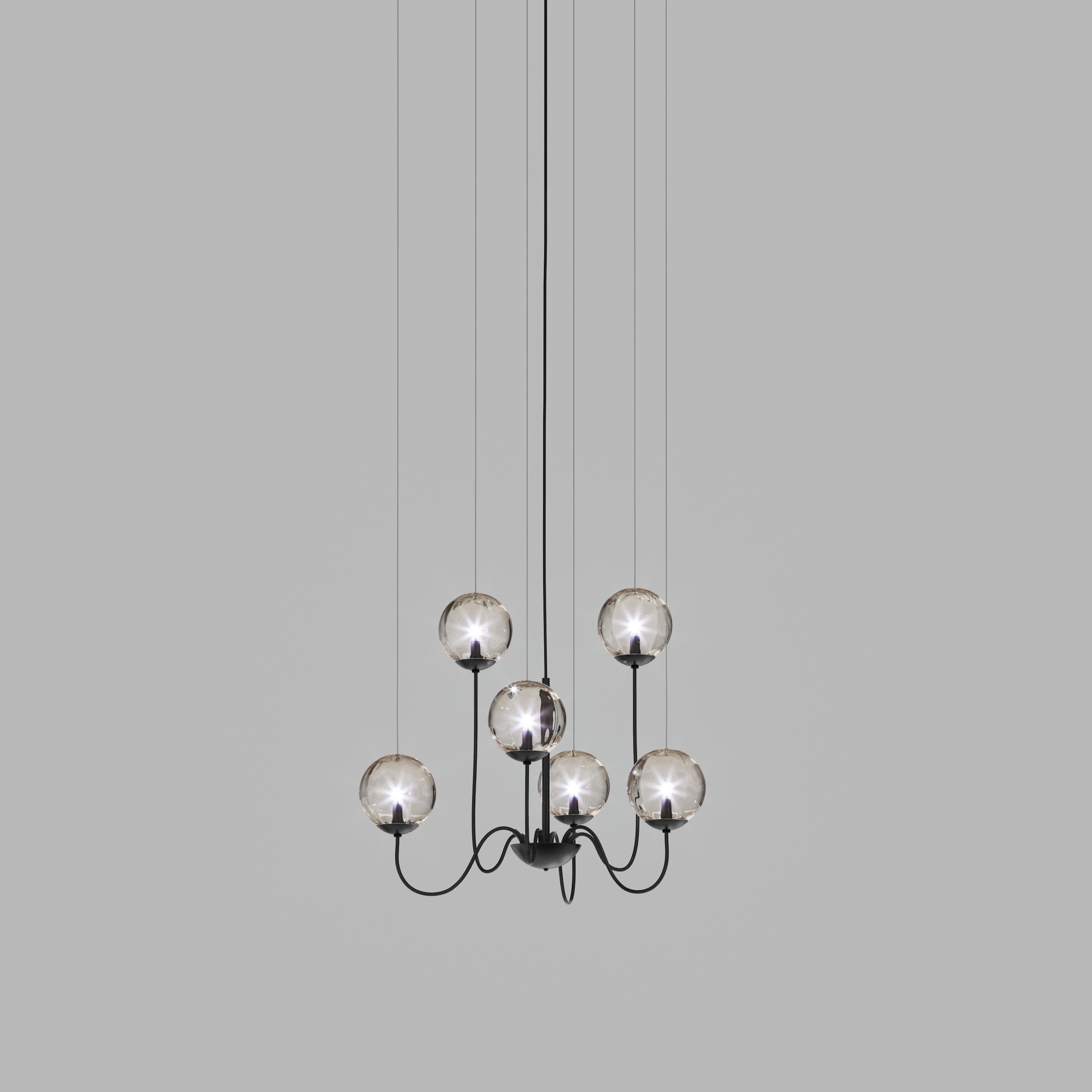 Collezione di lampade con diffusore in vetro soffiato e irregolare a righe. Le tre dimensioni delle sfere e le diverse altezze dei cavi sono pensate per creare composizioni eleganti. La versione lampadario permette di fissare i diffusori con cavi