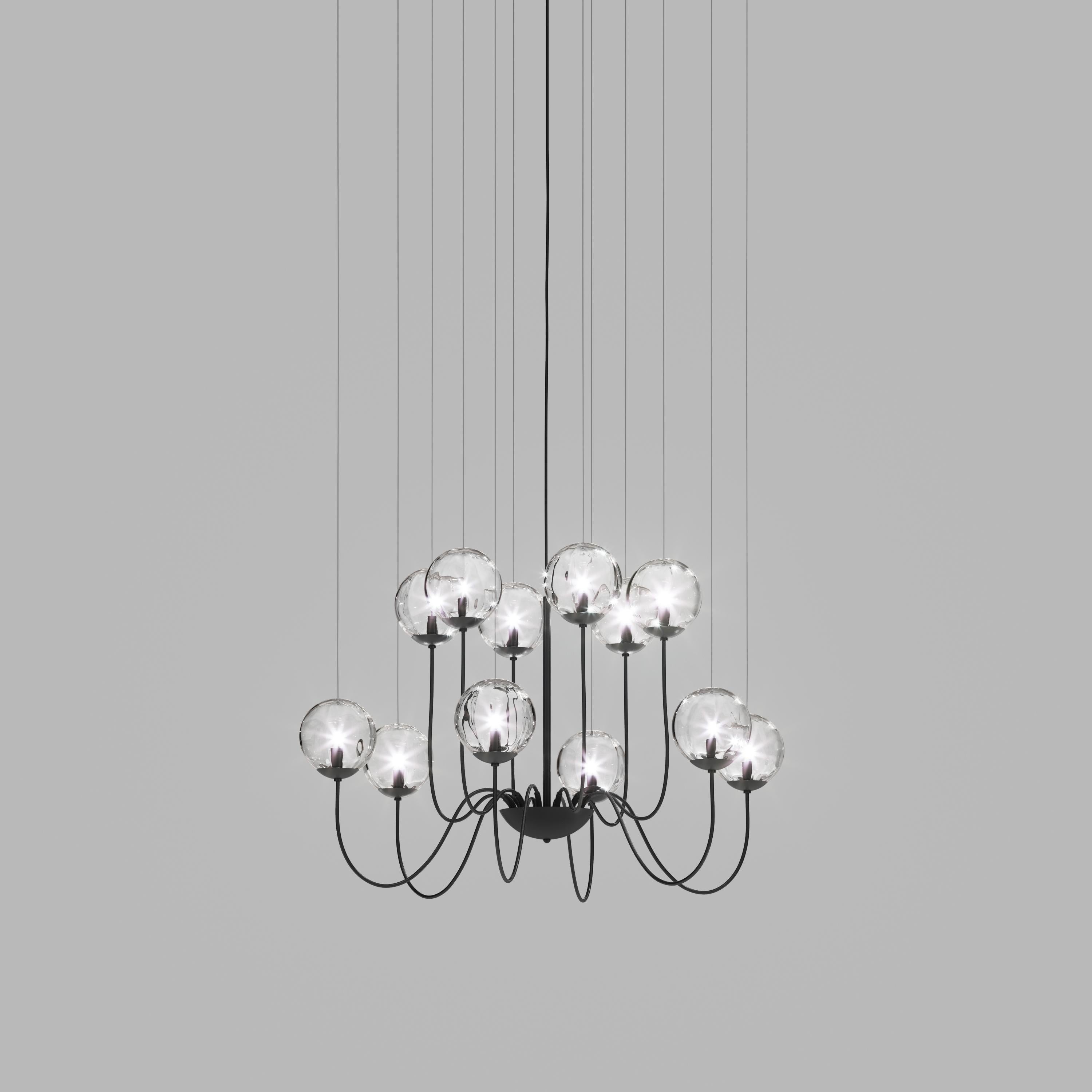 Collezione di lampade con diffusore in vetro soffiato e irregolare a righe. Le tre dimensioni delle sfere e le diverse altezze dei cavi sono pensate per creare composizioni eleganti. La versione lampadario permette di fissare i diffusori con cavi