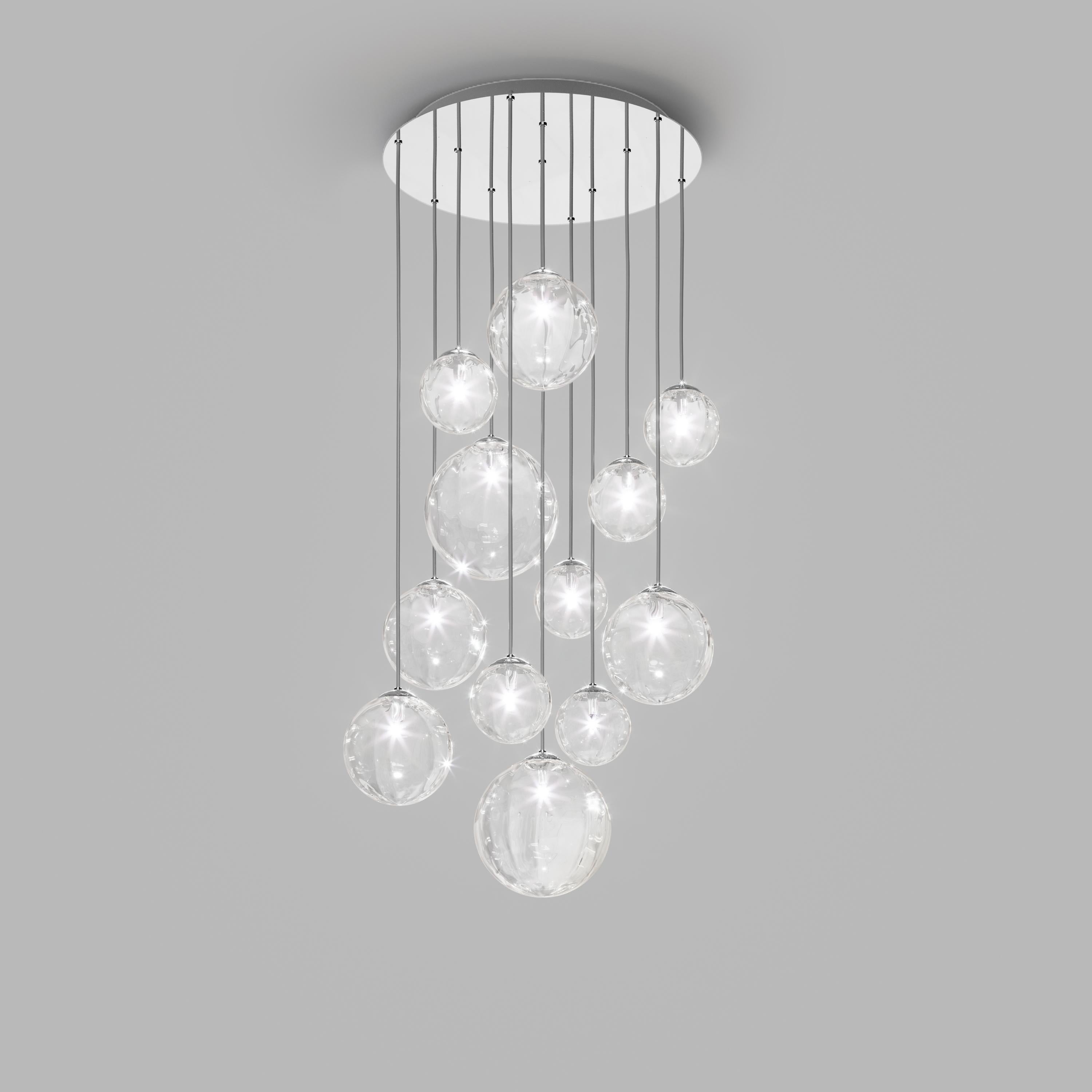 Collection of lamps with a blown and irregular striped glass diffuser. The three sizes of the spheres and the different cable heights are designed to create elegant compositions. The chandelier version allows to fix the diffusers with steel cables