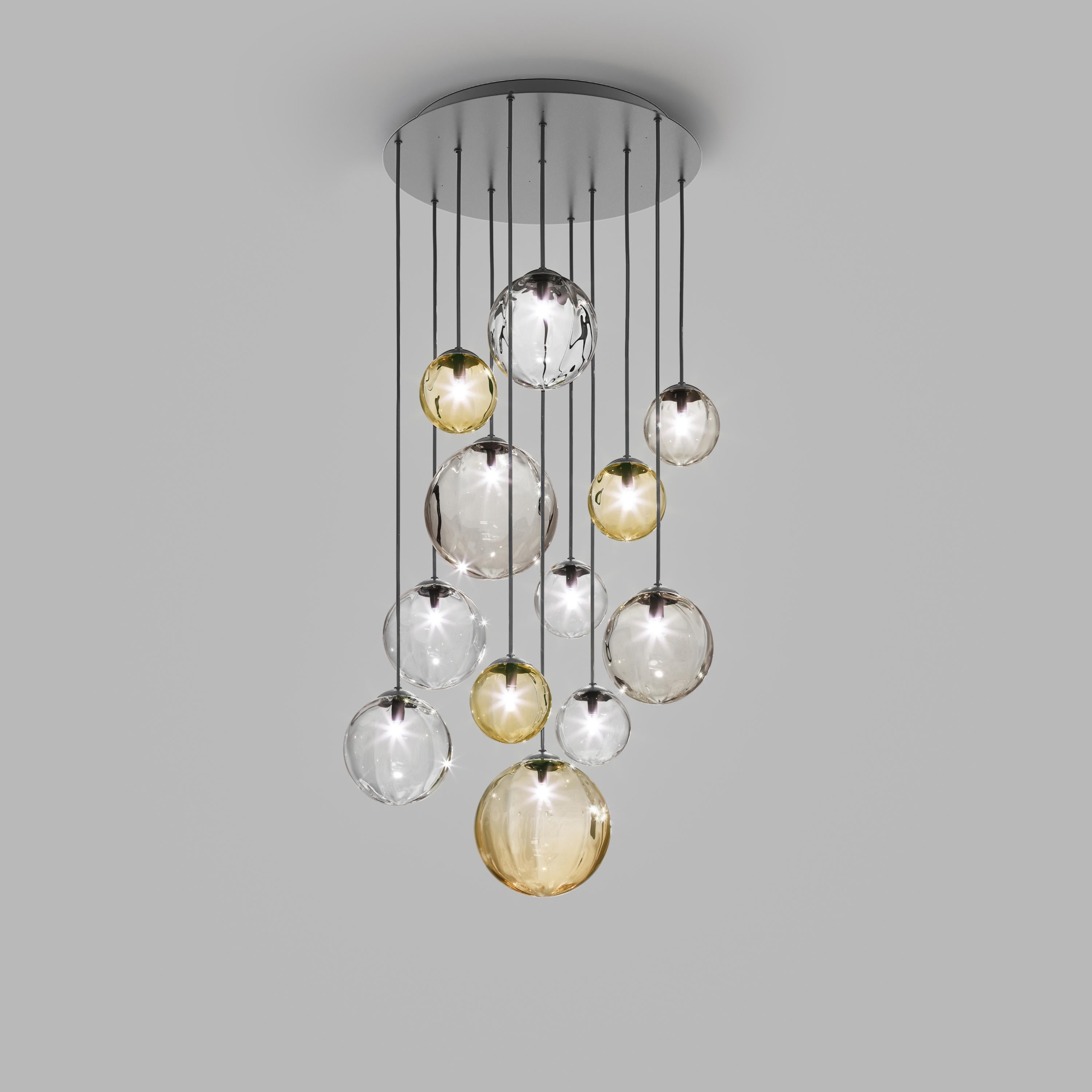 Collection of lamps with a blown and irregular striped glass diffuser. The three sizes of the spheres and the different cable heights are designed to create elegant compositions. The chandelier version allows to fix the diffusers with steel cables