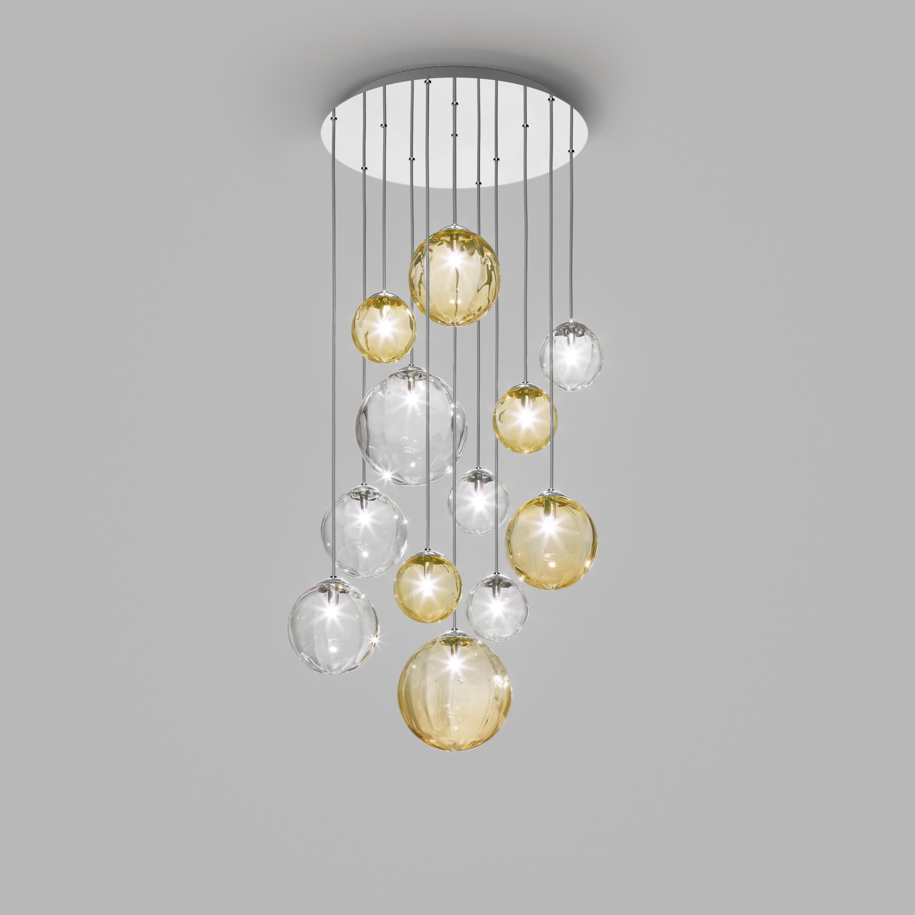 Collection of lamps with a blown and irregular striped glass diffuser. The three sizes of the spheres and the different cable heights are designed to create elegant compositions. The chandelier version allows to fix the diffusers with steel cables