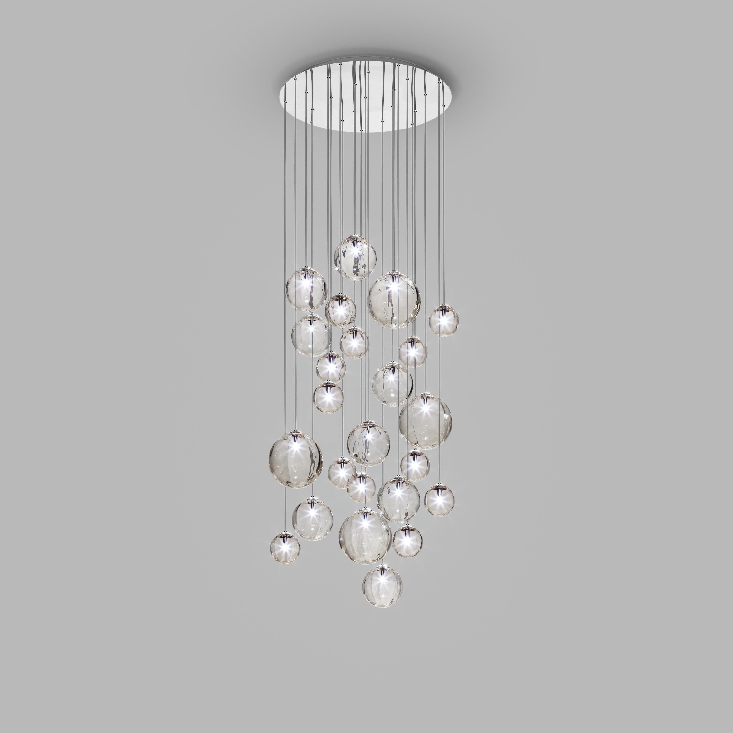 Collection of lamps with a blown and irregular striped glass diffuser. The three sizes of the spheres and the different cable heights are designed to create elegant compositions. The chandelier version allows to fix the diffusers with steel cables