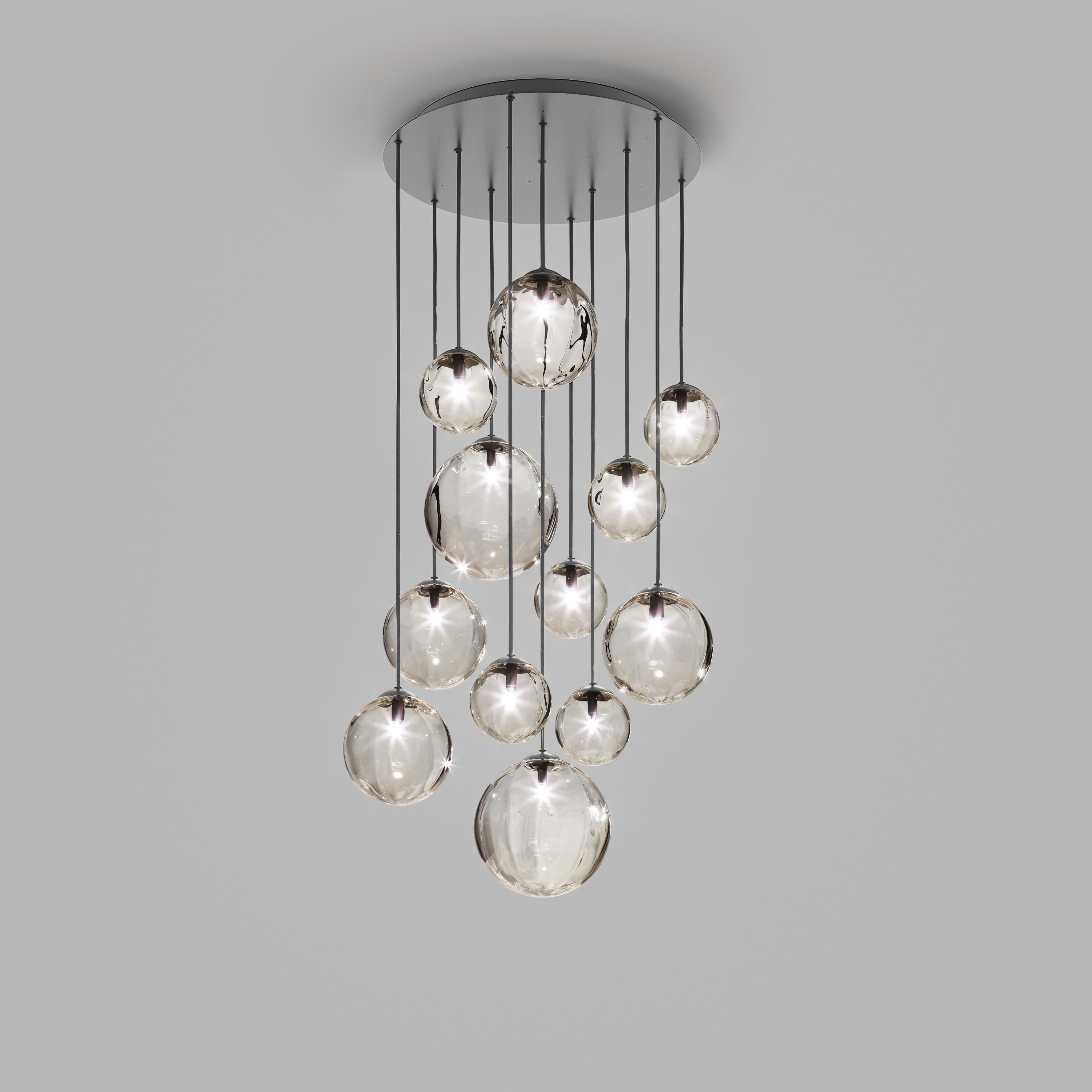 Collection of lamps with a blown and irregular striped glass diffuser. The three sizes of the spheres and the different cable heights are designed to create elegant compositions. The chandelier version allows to fix the diffusers with steel cables