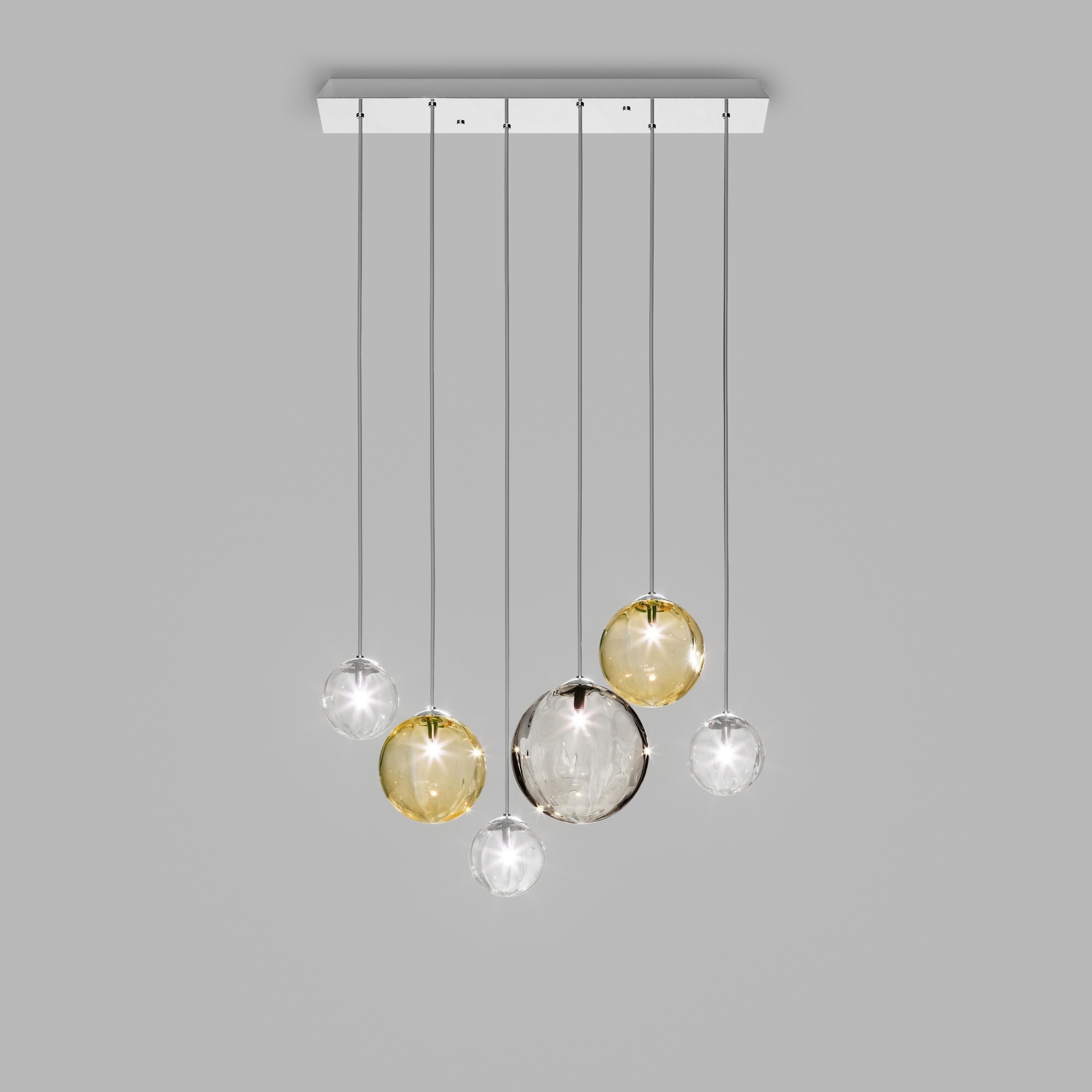 Collection of lamps with a blown and irregular striped glass diffuser. The three sizes of the spheres and the different cable heights are designed to create elegant compositions. The chandelier version allows to fix the diffusers with steel cables