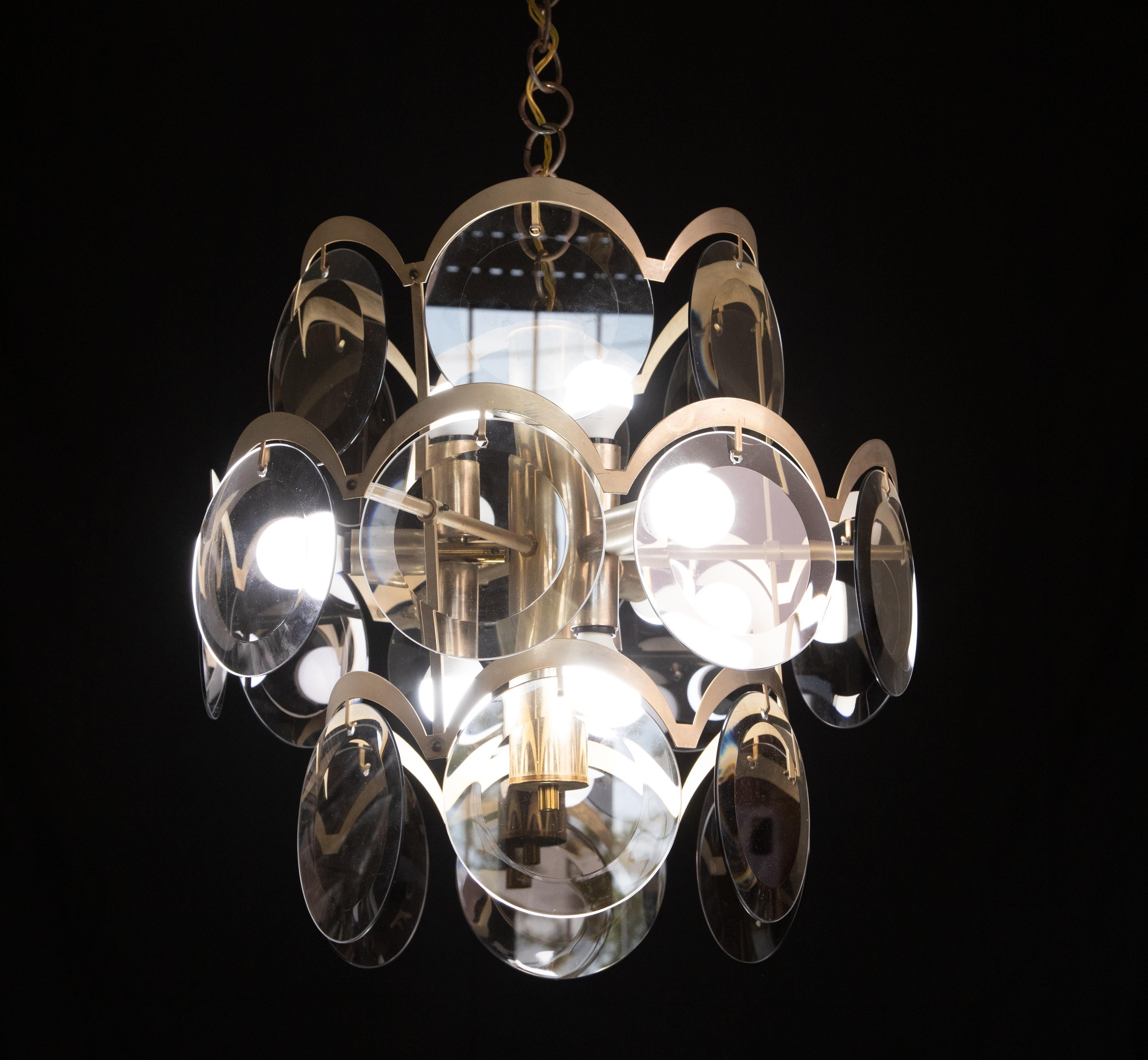 Vintage Italian chandelier with three tiers of smoked glass discs mounted on a brass frame, with a crescent-shaped brass arch above each disc / Designed and made by VIstosi in Italy, circa 1960
9 lights or E14
Measurements: diameter 55 inches,