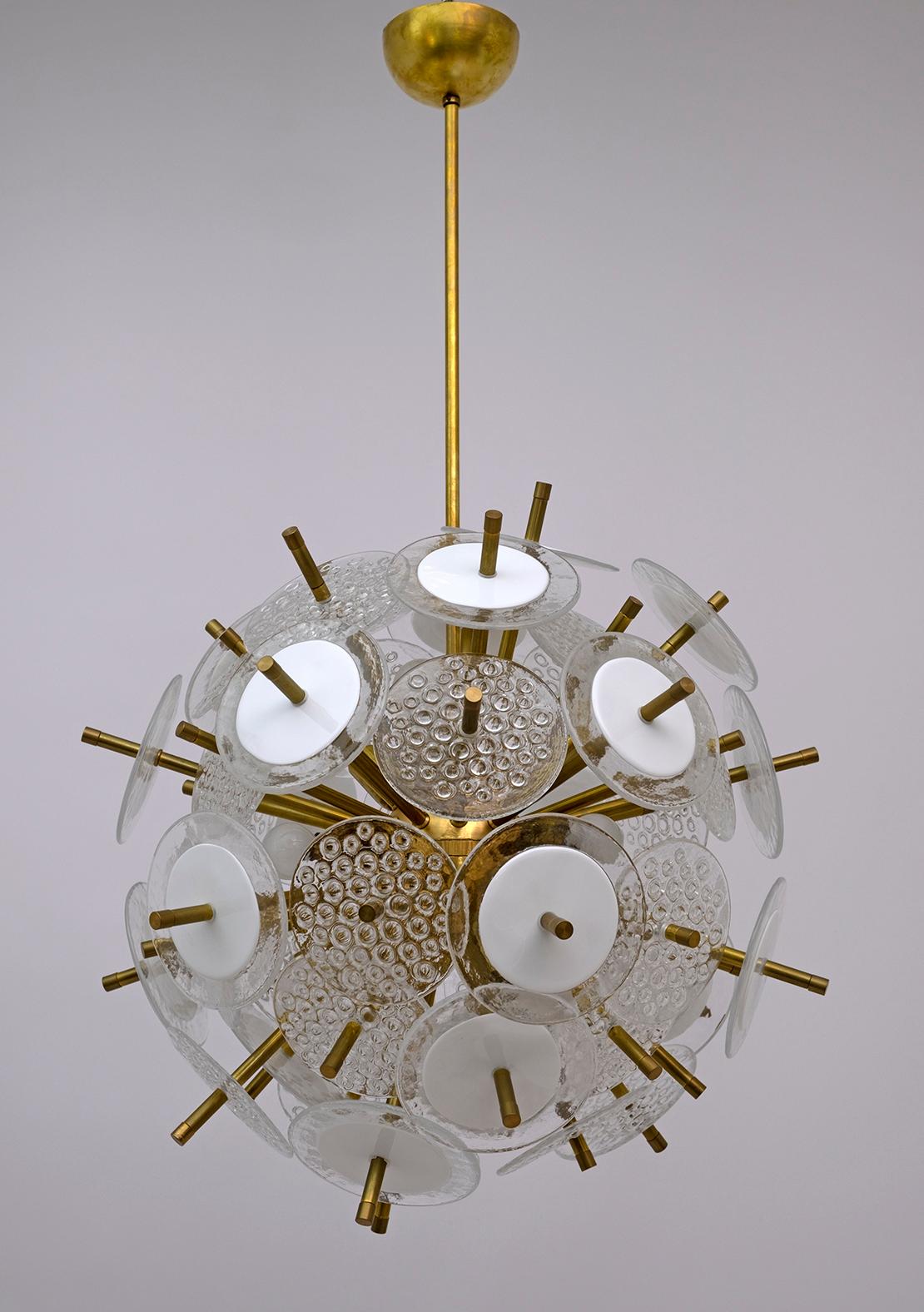 This sophisticated modernist Sputnik chandelier by Vistosi has a satin brass structure with a spherical core from which it frees itself very well. At the end of each rod is a white hand blown Murano glass disc surrounded by a translucent perimeter