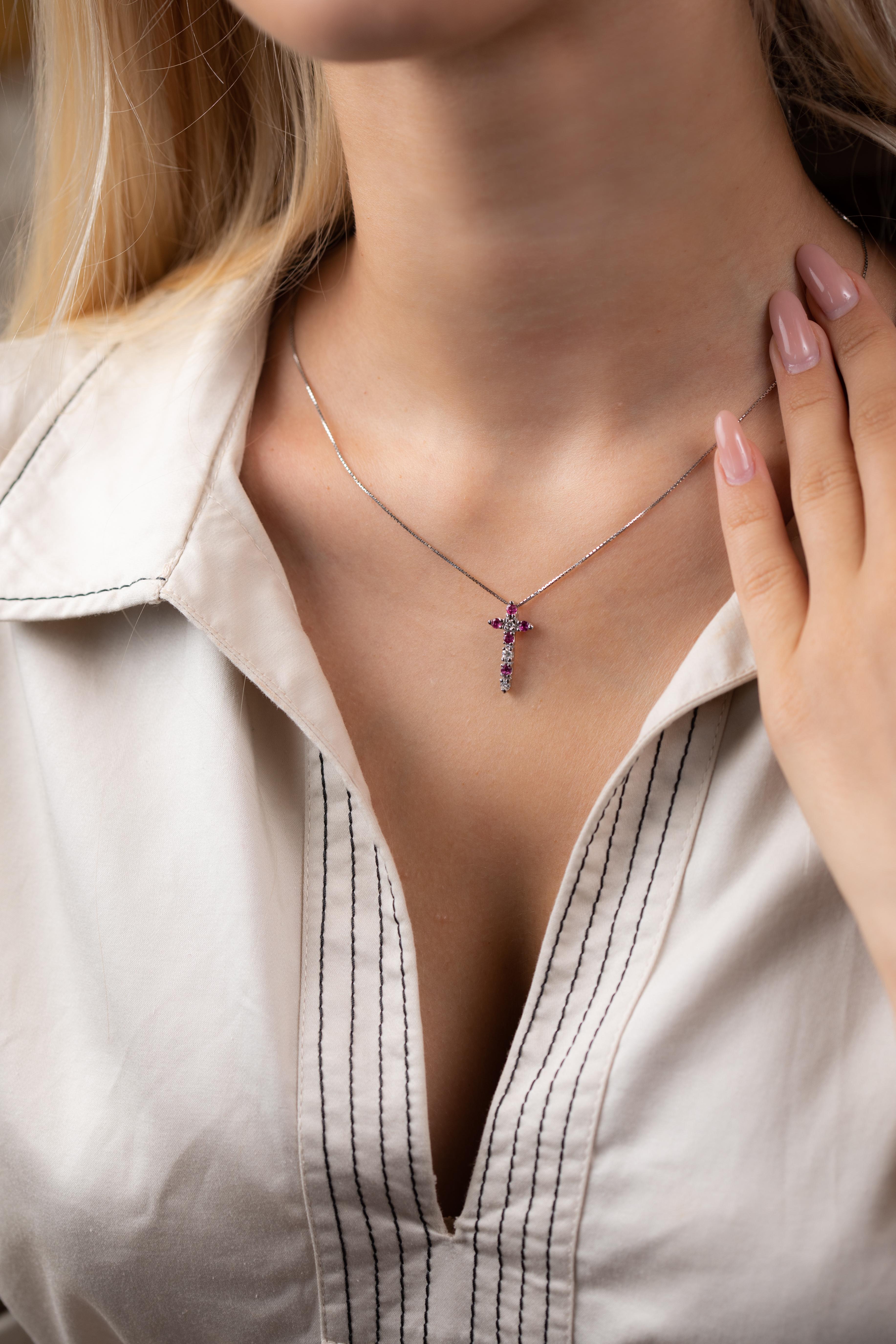 Il ciondolo a forma di croce elegante in oro bianco 18 carati appartiene alla collezione Timeless.  La croce è decorata da diamanti bianchi naturali per un totale di 0,15 carati e rubini naturali per un totale di 9,5 carati. Il peso totale del