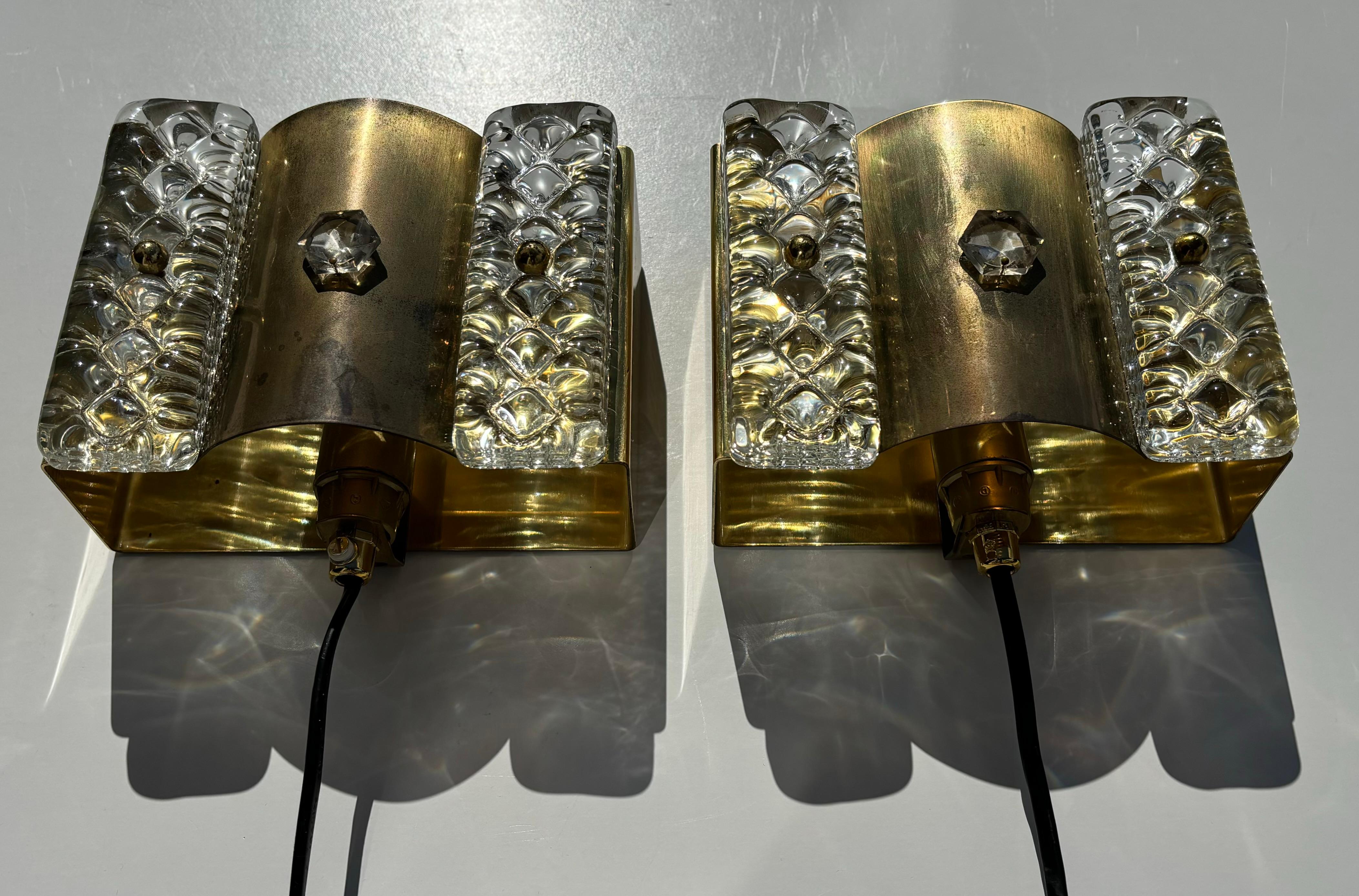 Pair of Danish midcentury modern brass, art glass wall sconces made by Vitrika in the 1960s. Square shaped brass mount with two clear textured solid glass pieces on each side. One light labelled on the back. Wired for Europe and the US with fitting