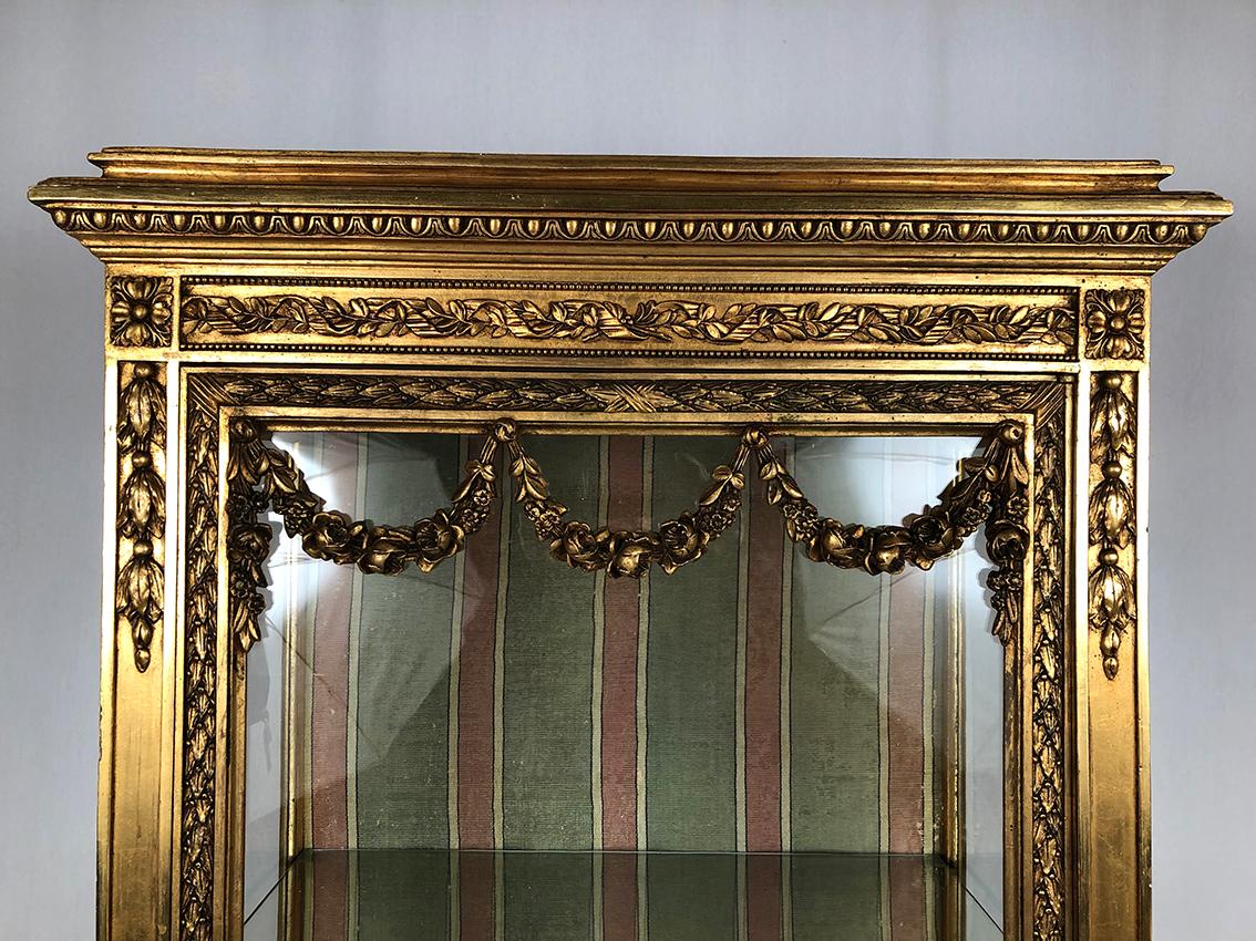 Vitrine de style Louis XVI en bois et stuc doré, vers 1900
Ouvre à une porte sur deux étagères en verre
Intérieur tapissé d’un tissu à rayures (usures)
Repose sur quatre pieds cannelés et fuselés
Bel état général
La clé ne tourne plus et fait office