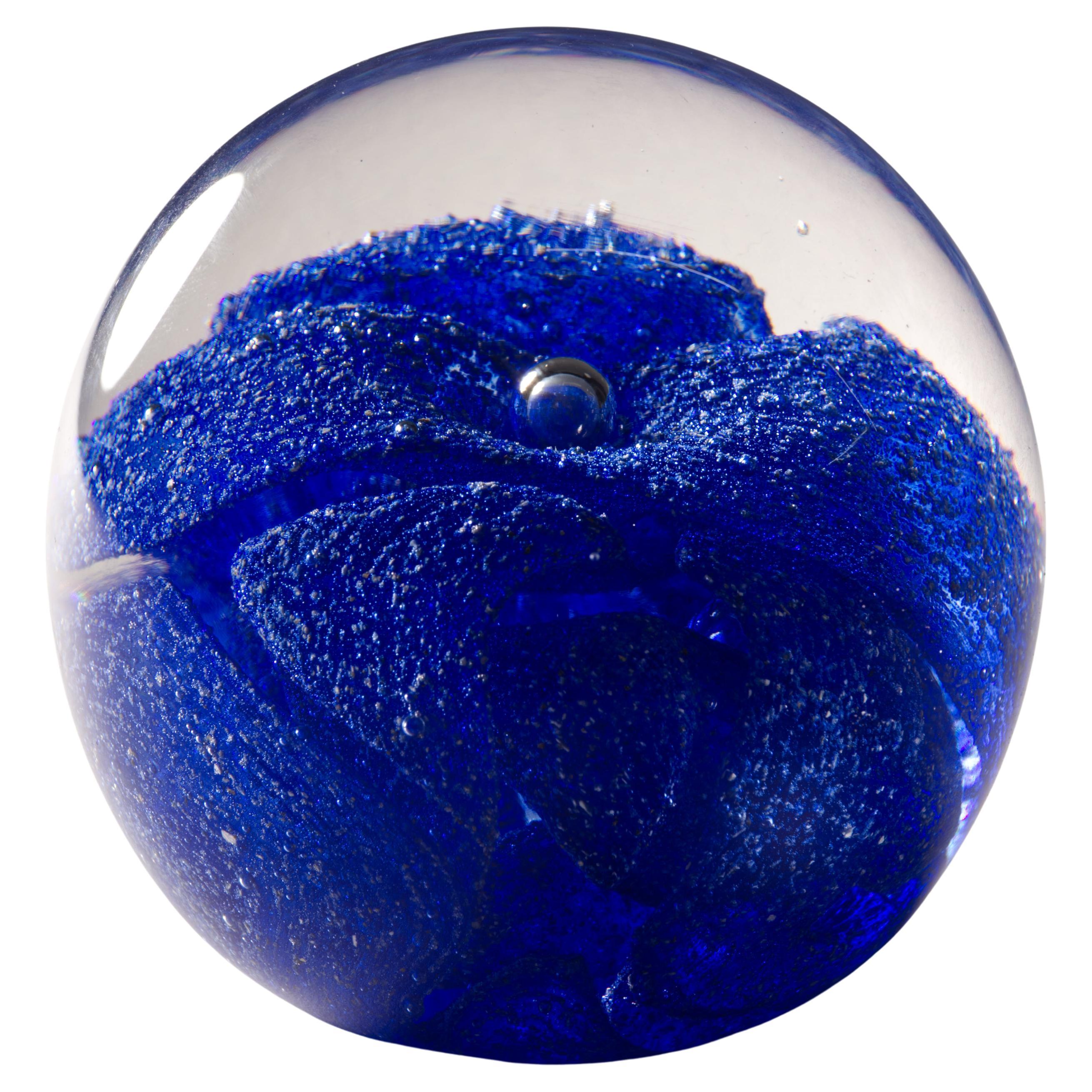  Raro pisapapeles de vidrio fundido que presenta un centro redondeado de color con remolinos de vidrio azul colocados en un patrón abstracto y gráfico, con toda la estructura encerrada en vidrio transparente en técnica de sommerso. Los sutiles