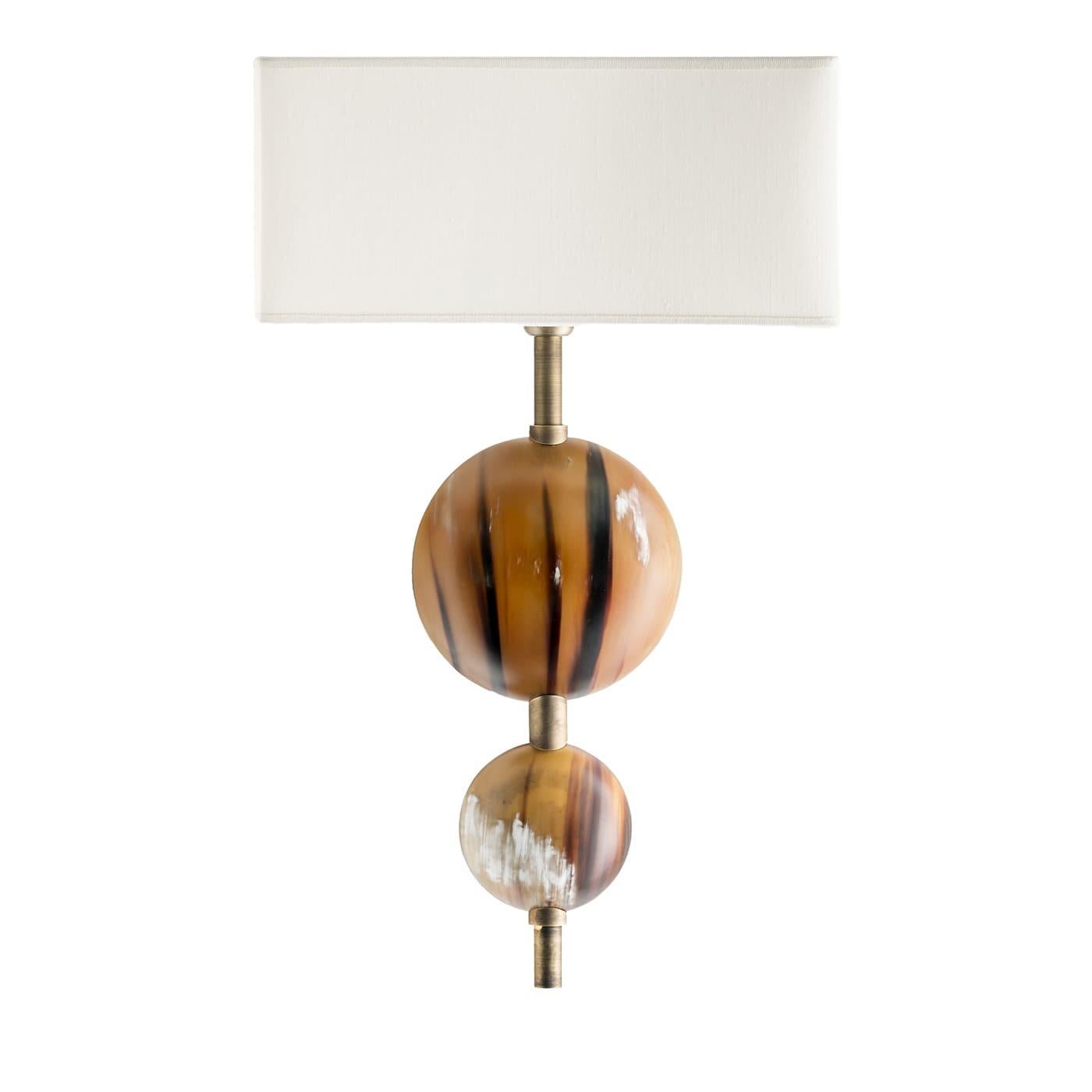 Perfecto para acentuar exclusivas decoraciones modernas con un refinado toque exótico, este aplique revela sofisticación detalle tras detalle. Coronado por una luminosa pantalla de fino tejido shantung marfil, el armazón de latón está enriquecido