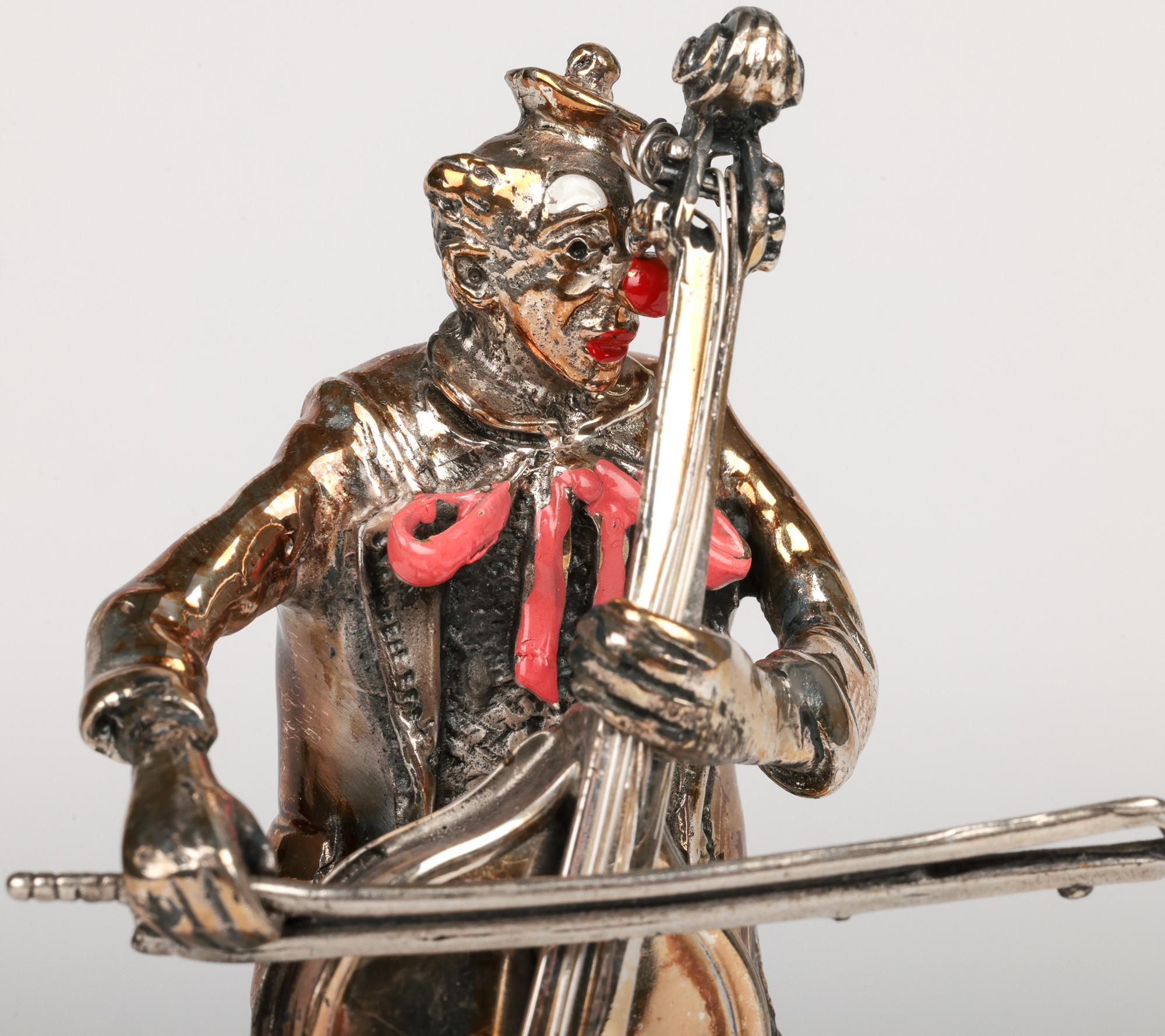 Ravissante figurine de clown musical en verre de Murano et en argent datant du milieu du siècle dernier, réalisée par Vittorio Angini et datant d'environ 1960. Le personnage debout joue d'un Cello qu'il tient dans sa main gauche, appuyé contre sa