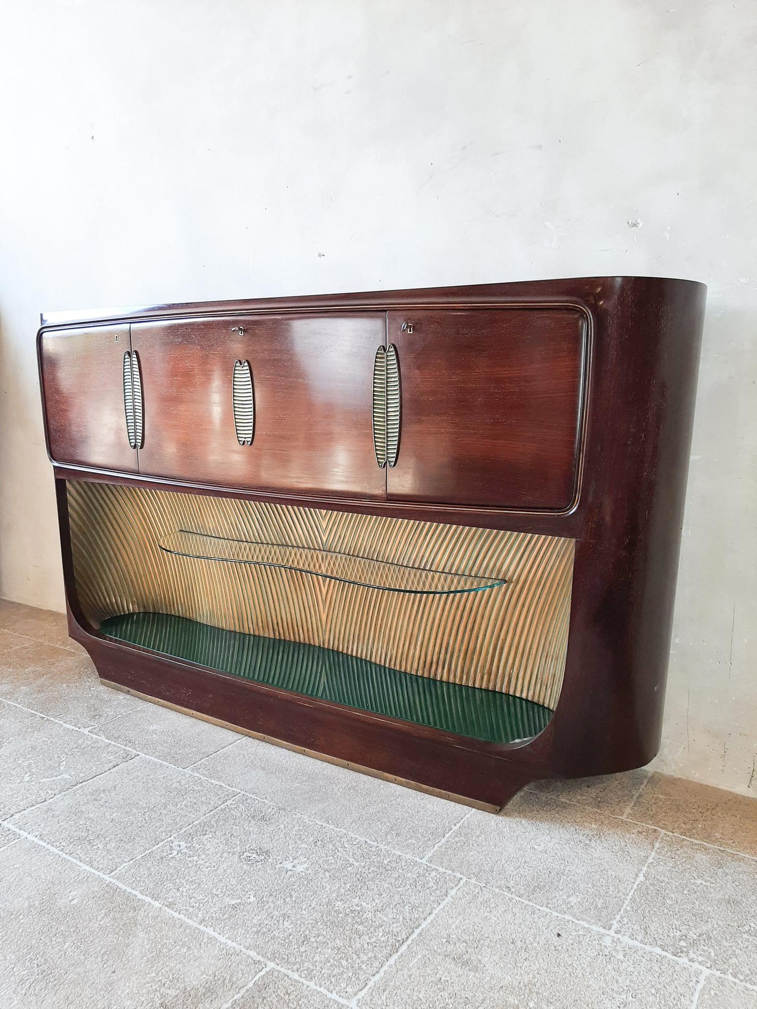 Vittorio Dassi design drybar / sideboard for Palazzi dell’Arte Cantù.

Rosewood bar cabinet with two side doors, mirrored central bar compartment with flap opening and lights, front decorations in brass, upper and lower top in green glass, above