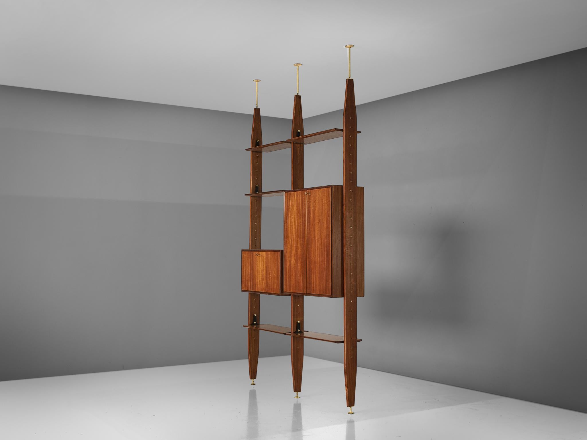 Vittorio Dassi, wall unit book shelf, in Brasillian hardwood and brass, Italy, 1960s.

This book shelf features a three legged structure that can freely be fixed between the ceiling and the floor. In between the legs the shelves and storage space