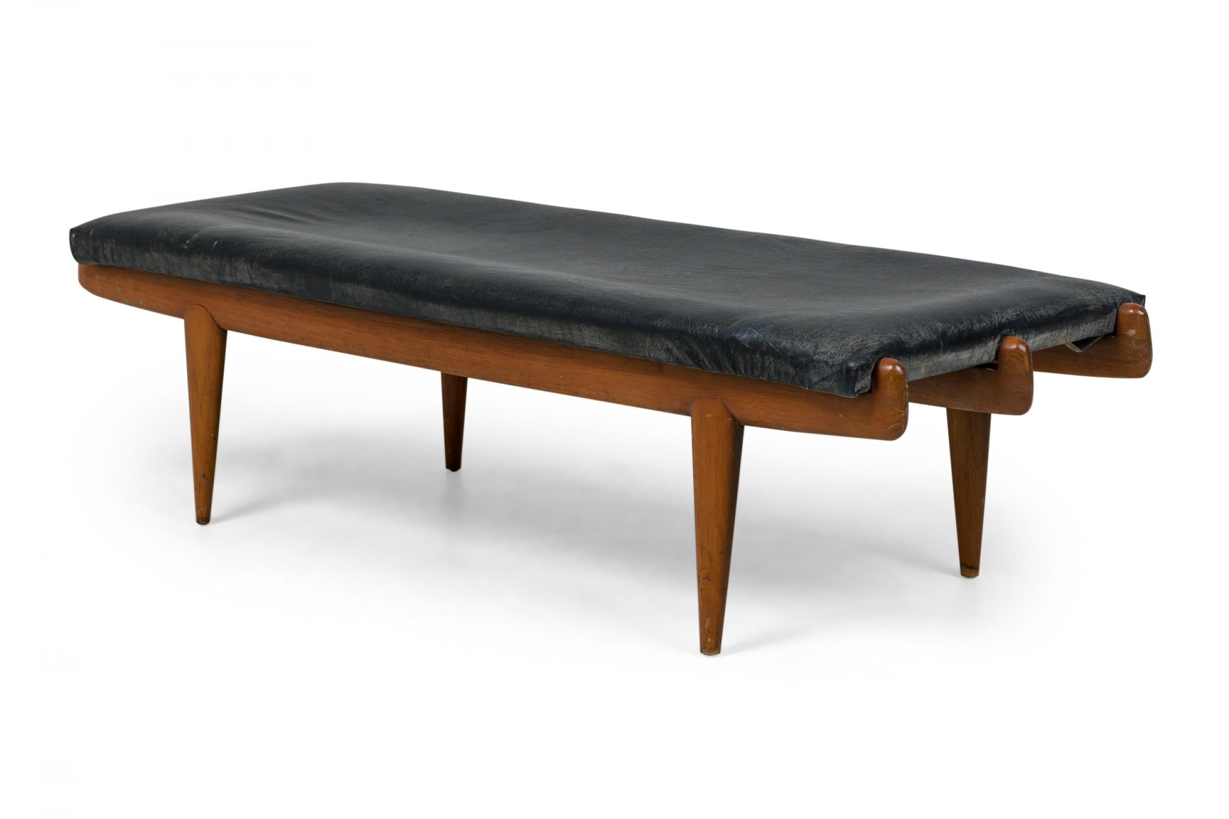 Midcentury Italian Modern walnut bench in sculptural form features a 3-row frame with rounded edges, rectangular seat cushion upholstered in black leather, standing on 4 short conical legs. (Vittorio Dassi).